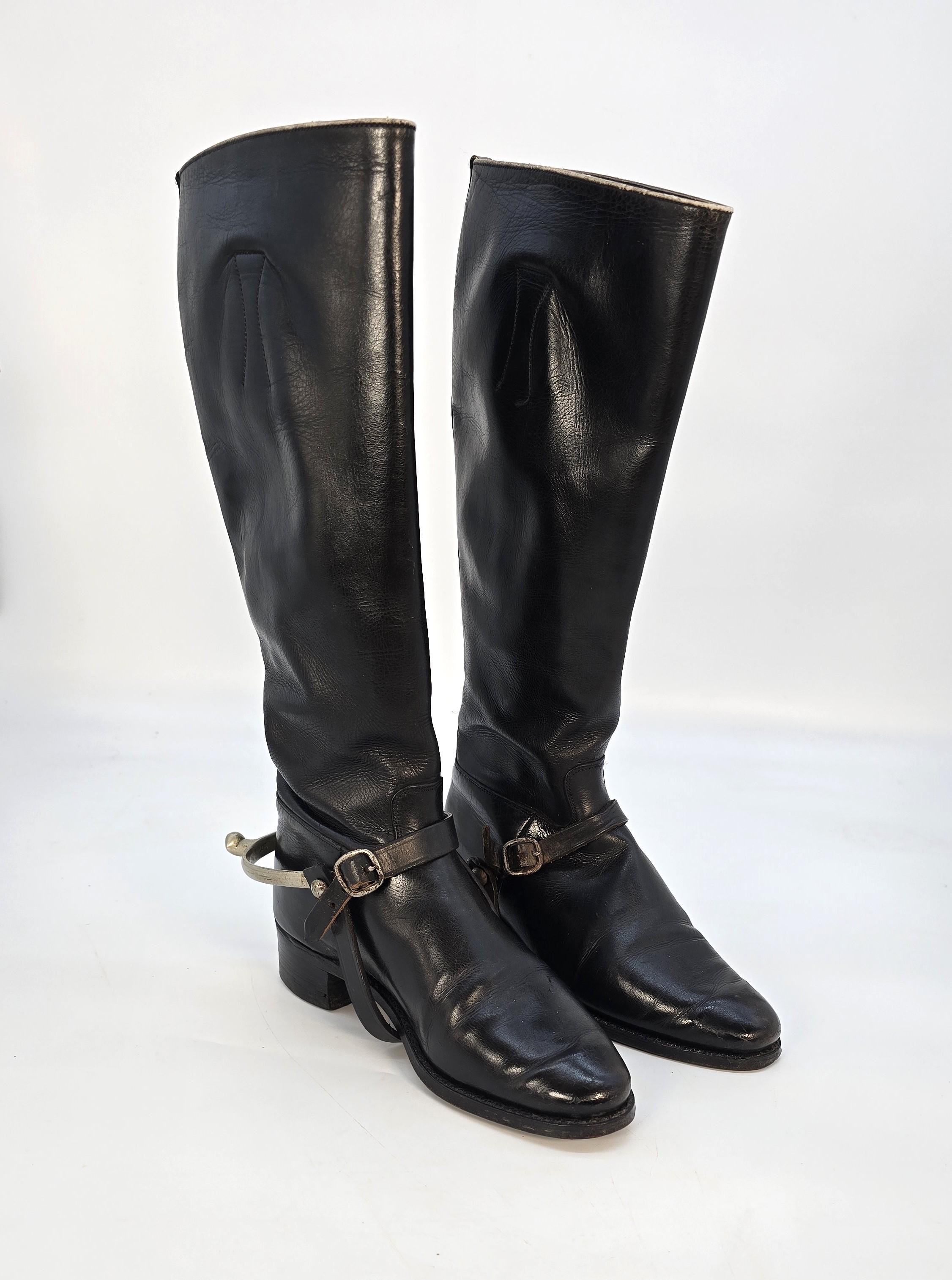 Interesante y decorativo grupo formado por un par de botas de montar de cuero negro hechas a mano de gran calidad con espuelas separadas, una fusta de cuero marrón y un par de ganchos para botas, junto con la procedencia de dos fotografías de época