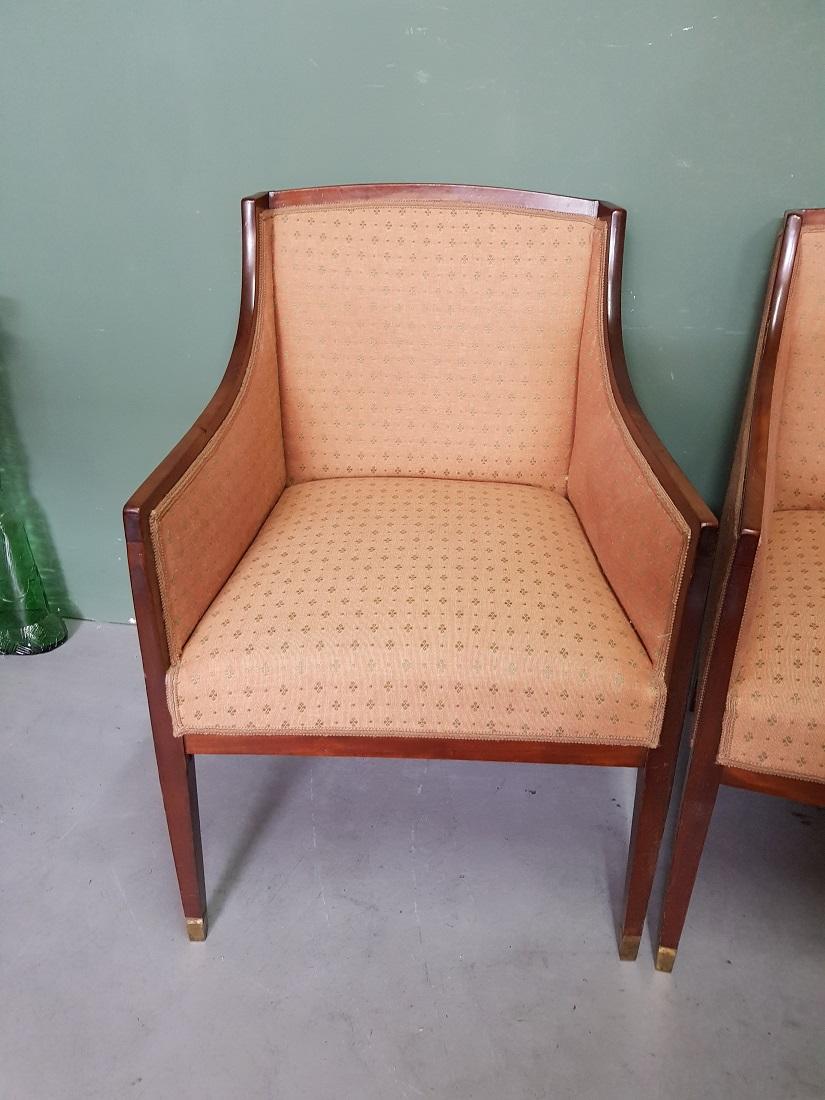 A pair of antique mahogany bergere chairs covered with a salmon-colored fabric with a returning motif and the 2 front legs decorated with a bronze base, both are in good condition with light user marks all around. Originating from the beginning of