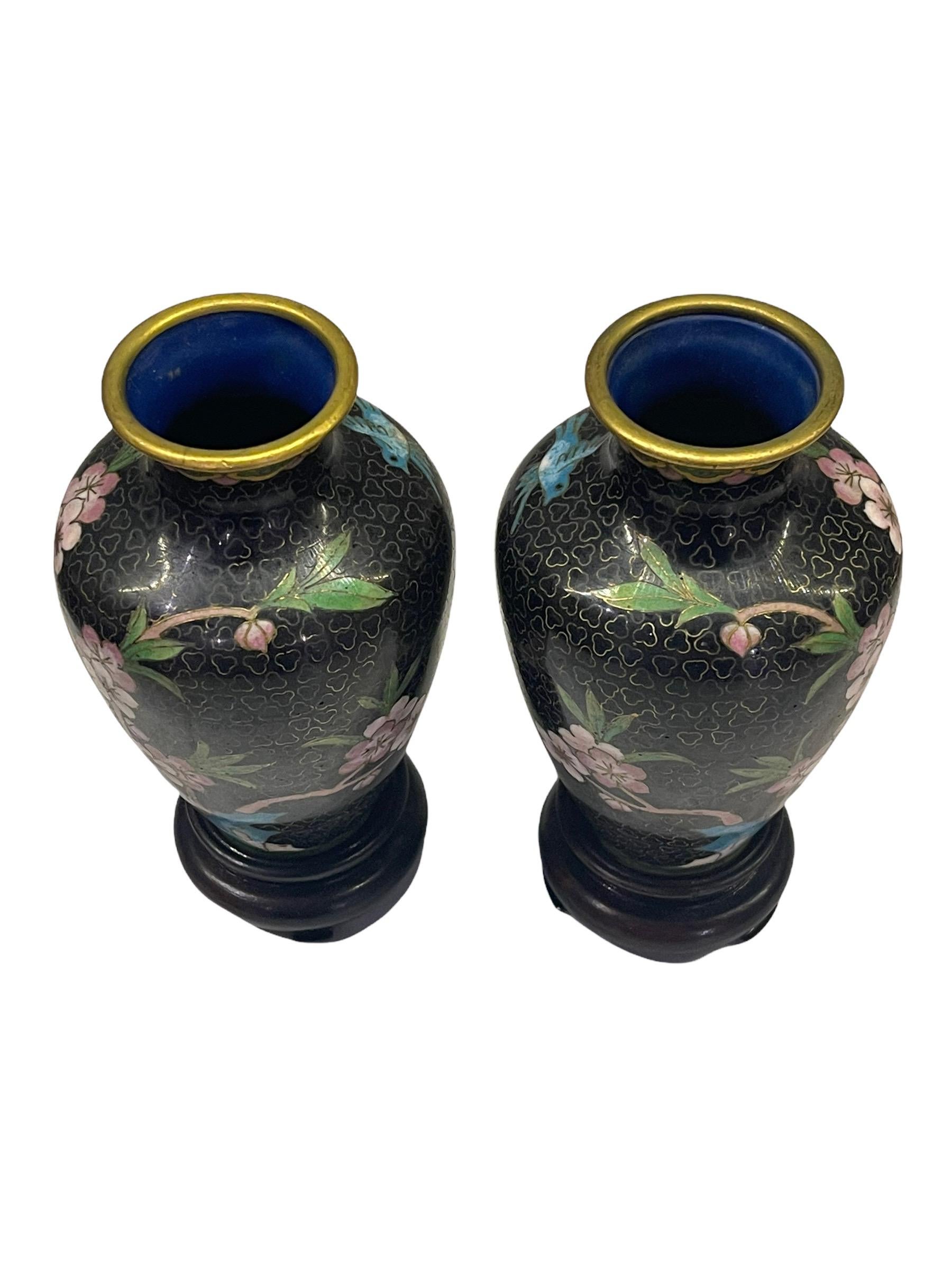 A pair of early 20th Century (Republic Period) Chinese urn vases created in the traditional cloisonne method. The miniature vases features brass metal forms with a classic baluster shape. The surface has been exquisitely hand decorated in colored