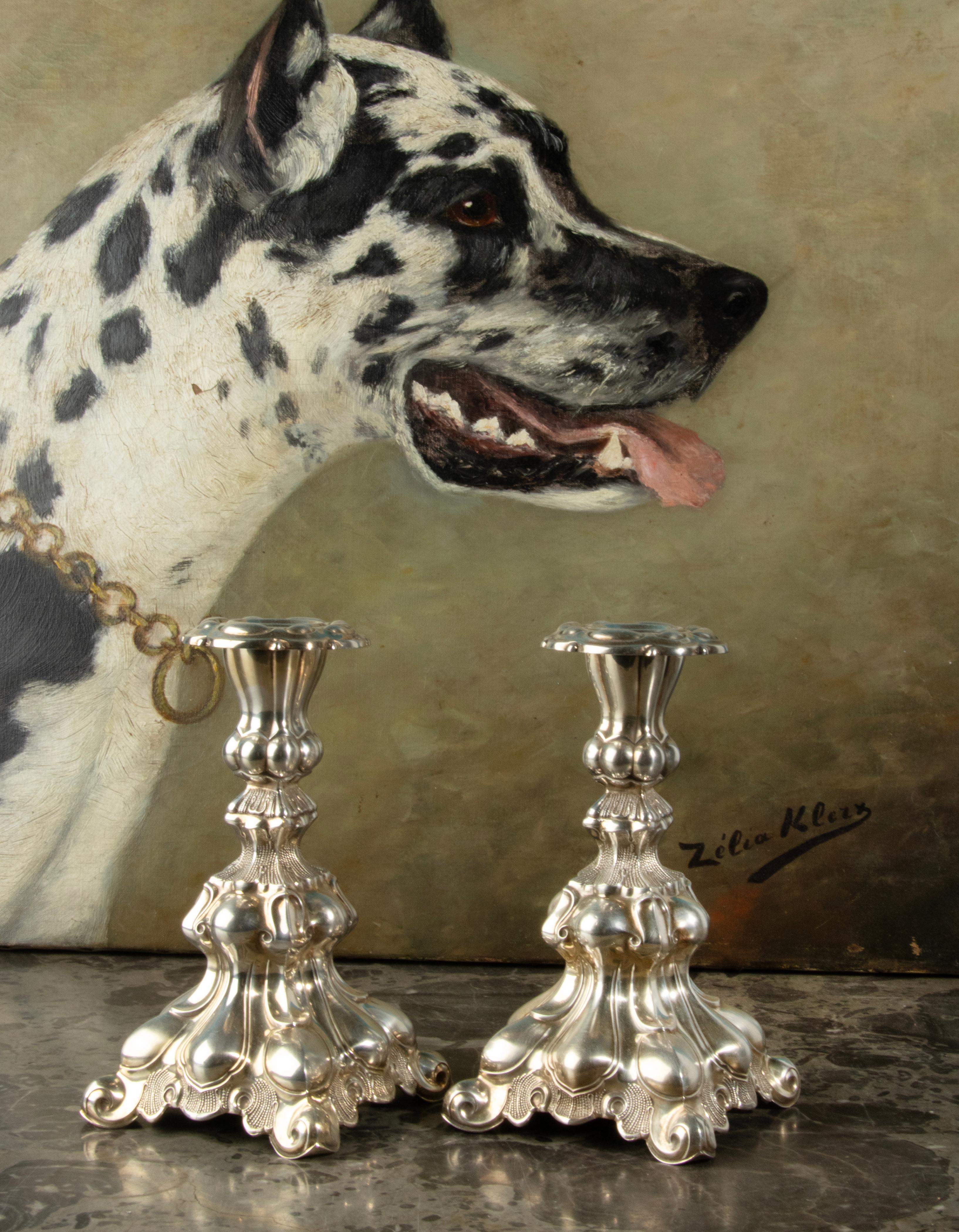 A beautiful pair of silver candlesticks, richly decorated with round shapes in Rococo style. The candlesticks are not hallmarked but have been tested and are solid silver. The foot is weighted from the inside and the bottom is covered with green