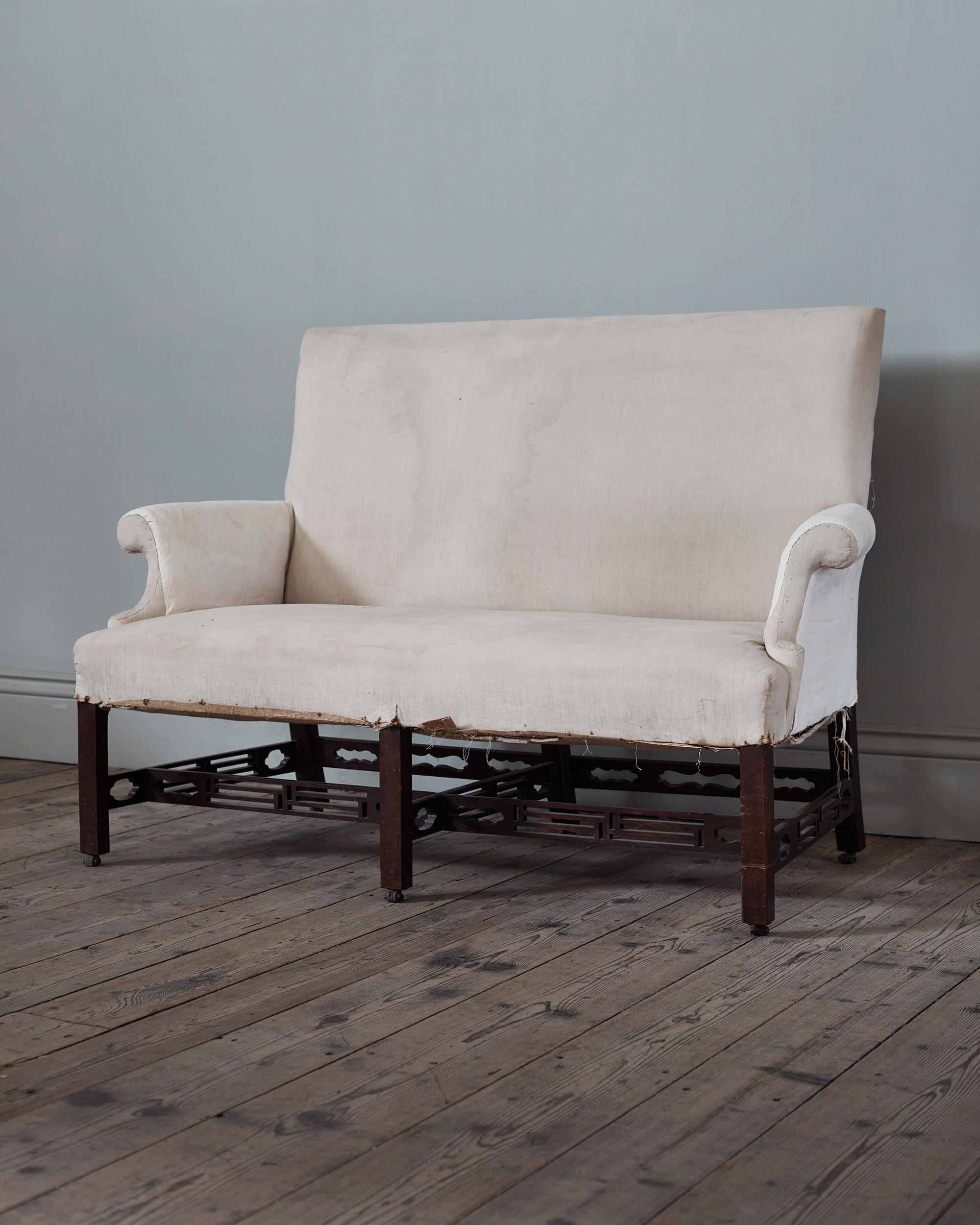 A Pair of Early George III Mahogany Sofas, c.1765

Of pleasingly compact form, with straight back and tightly curving C-scroll arms, with Chinese-Chippendale pierced stretchers and square legs terminating in their original leather casters. Stripped