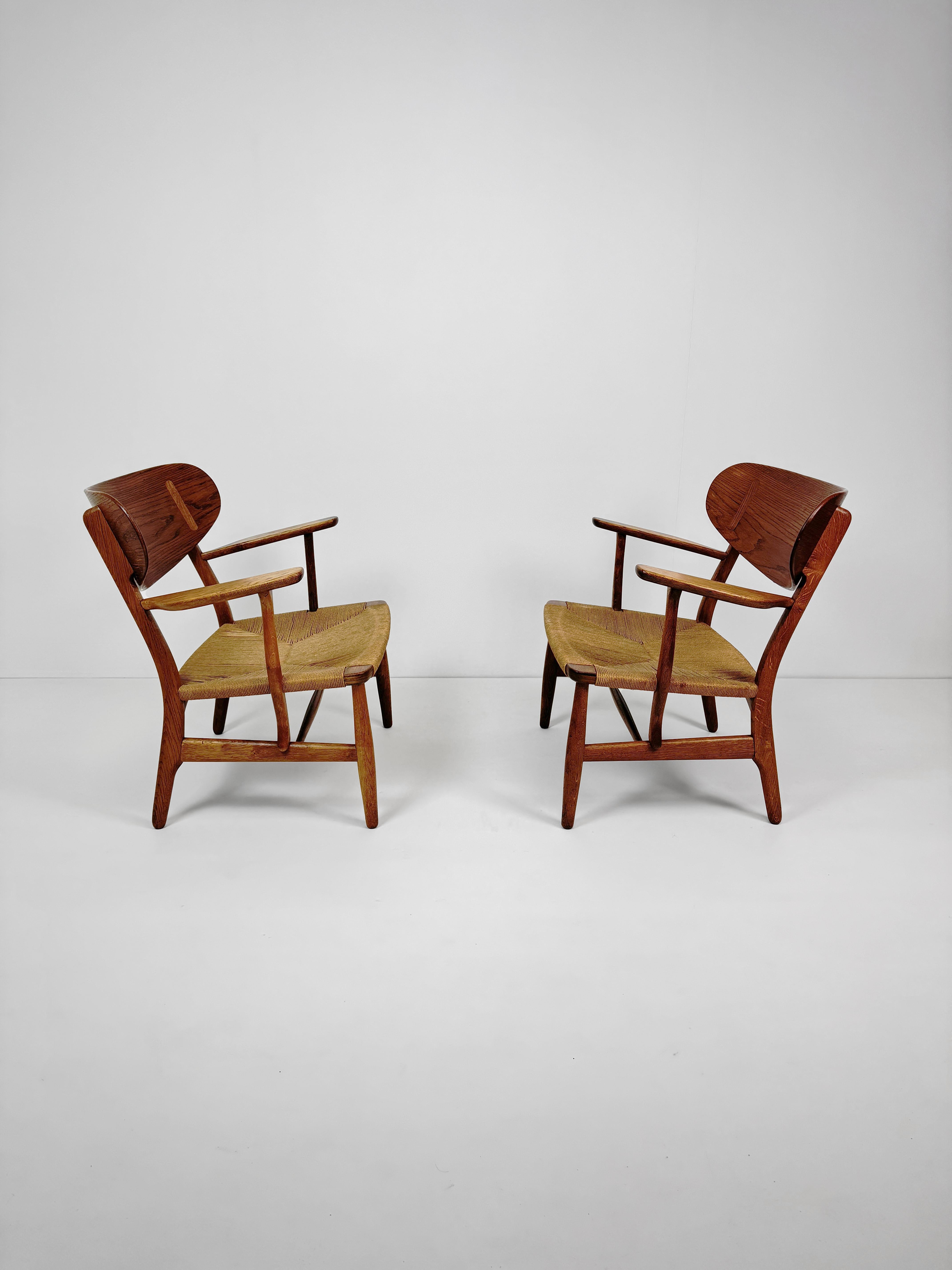 Paire de chaises de salon pour Carl Hansen & Son, modèle CH22, en chêne et cordon de papier, un exemple précoce de Hans J Wegner. Le bois de chêne présente une belle patine due au passage du temps. Les deux chaises sont en très bon état et les