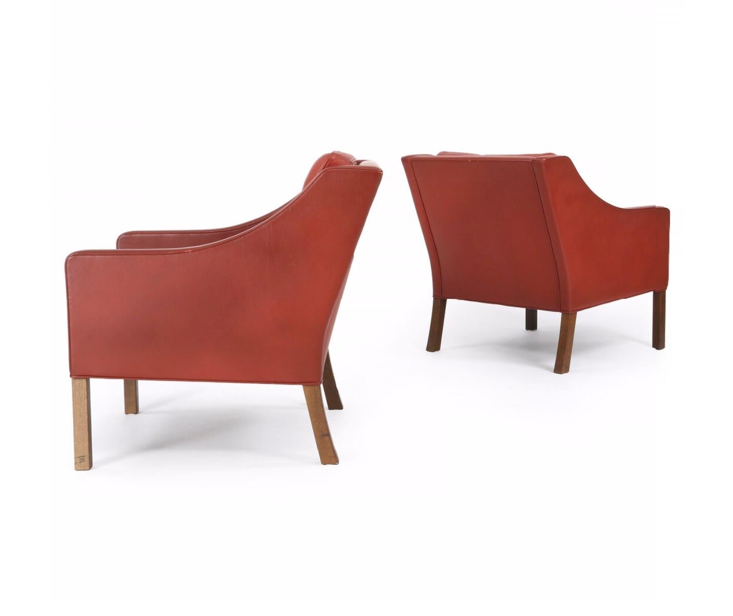 A pair of leather chairs with stained oak legs. Sides, back and loose cushions upholstered in terracotta coloured leather. Model 2207. Designed 1963.

Manufactured and marked by Fredericia Stolefabrik. 

Additional images, close-ups and detailed