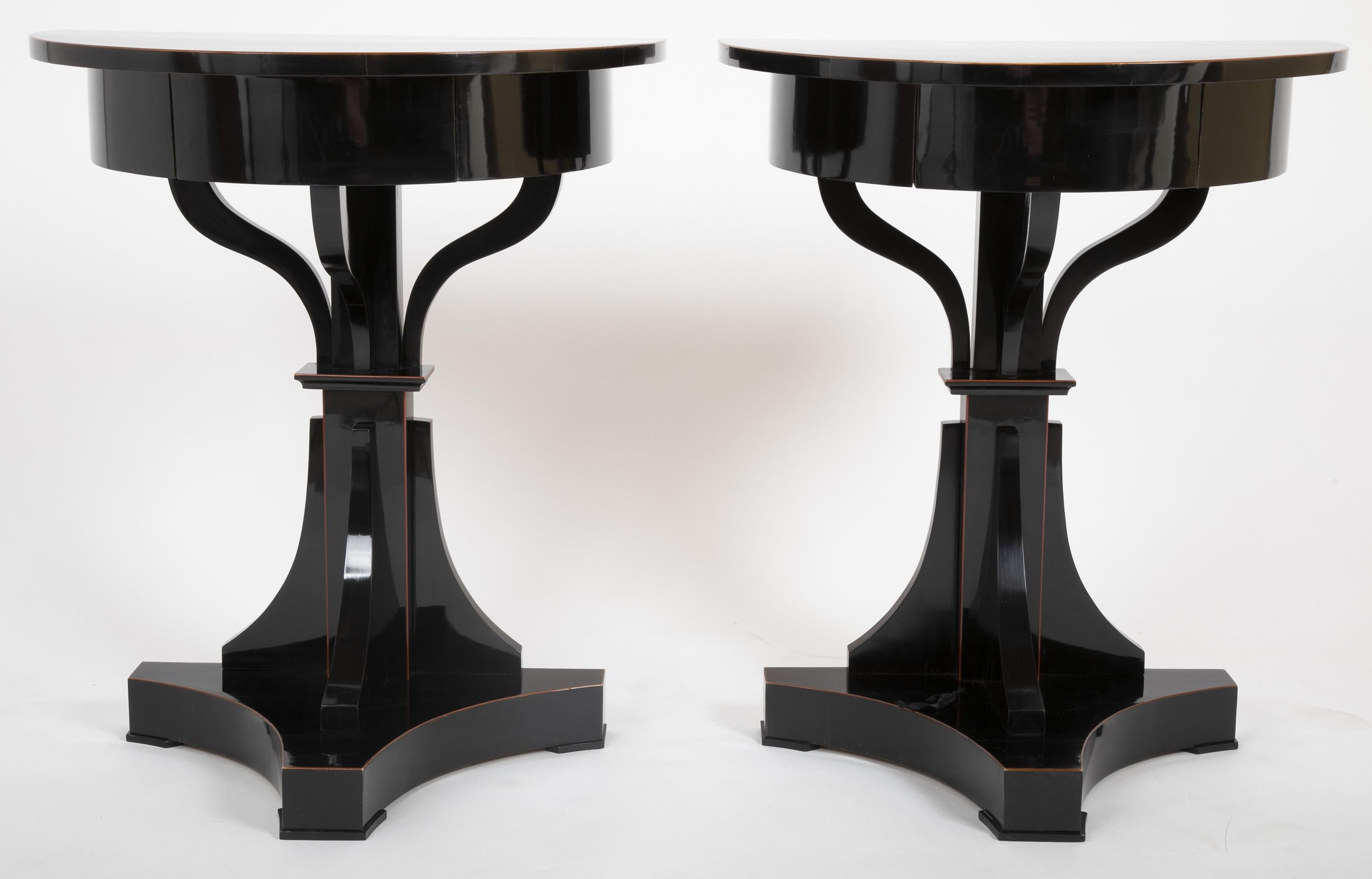 An interesting pair of 1830s Biedermeier demilune tables. Ebonized with mahogany tracery stringing.