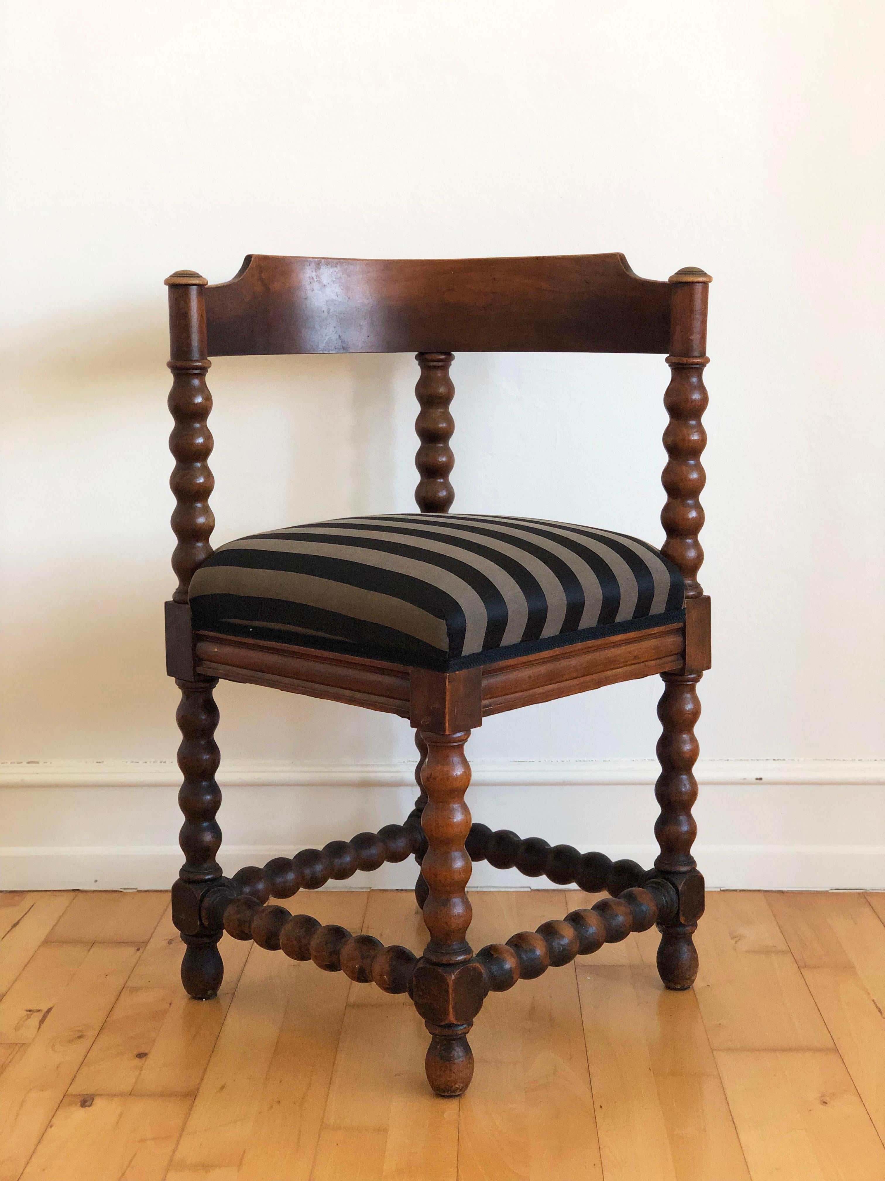 Antique pair of oak bobbin corner chairs, England, circa 1900. Crafted from solid oak, these corner chairs feature turned bobbin legs and simple, traditional lines showcasing the traditional English woodworking style. Both chairs feature upholstered