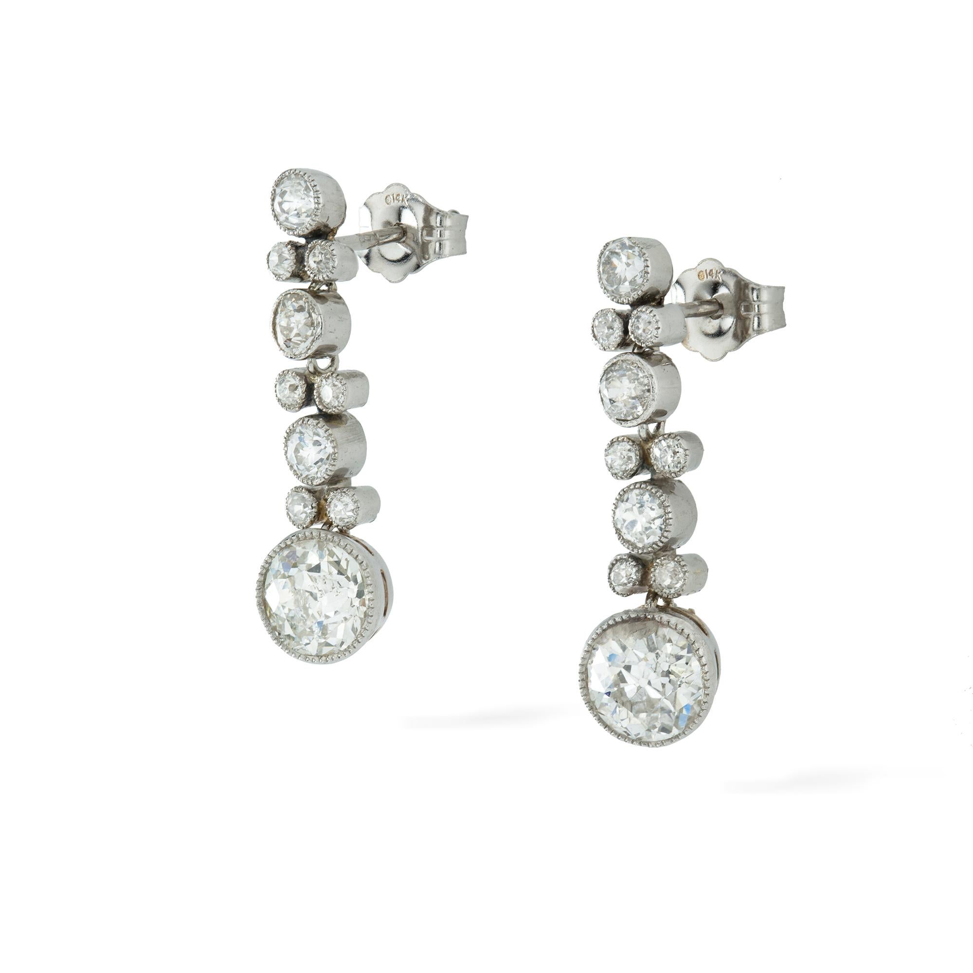 A pair of Edwardian diamond drop earrings, the two main old-cut diamonds weighing approximately 0.75 carats each millgrain-set, suspending from an old-cut diamond set run consisting of alternating eighteen smaller diamonds weighing approximately a