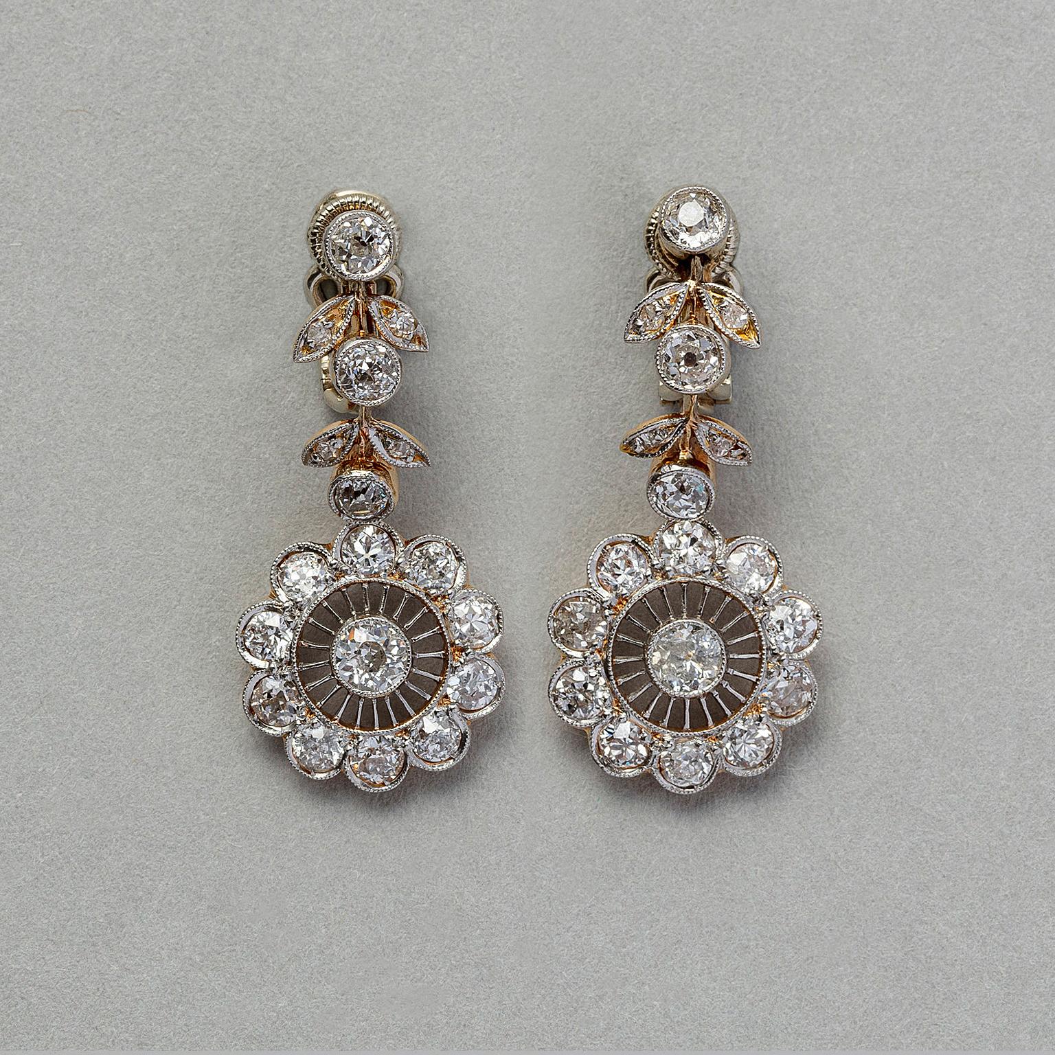 A pair of yellow gold and diamond earrings with 4 diamond leaves at the top around an old cut diamond. Underneath a flower with 10 smaller diamonds surrounding a center diamond (app, 2 carat), Edwardian 1910.

weight: 8.04 grams
dimensions: 3 x 1.2