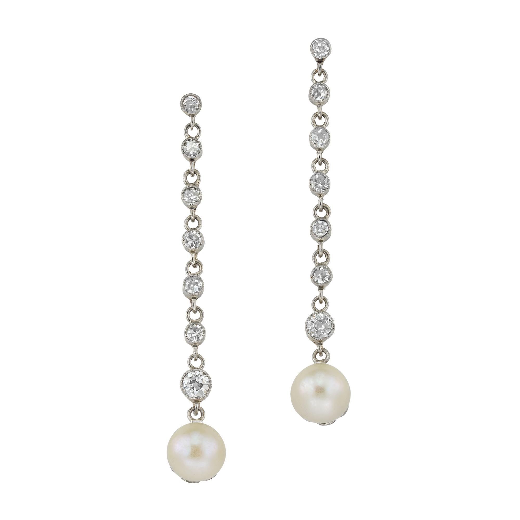 A pair of Edwardian natural pearl and diamond earrings, each earring with a button-shaped pearl measuring 6.2-6.3mm in diameter, accompanied by Gem & Pearl Lab report stating to be natural of saltwater origin, each pearl set in a fluted cut,