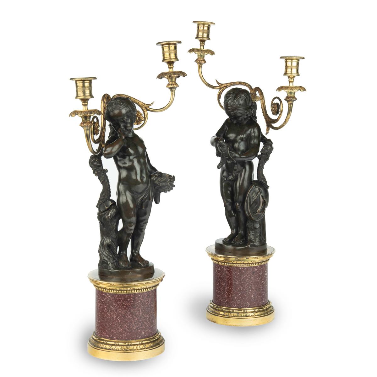 A pair of Egyptian porphyry and bronze candelabra after Charles-Antoine Bridan, each comprising a bronze figure and two candle branches set on a cylindrical porphyry base with ormolu mounts, one showing the figure of a young girl crying over an