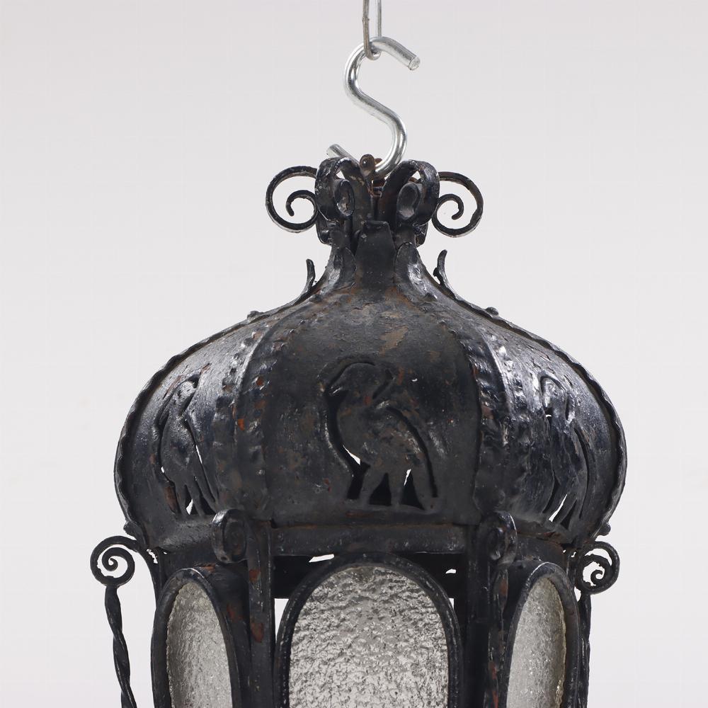 A pair of elaborate Italian wrought iron hanging lanterns C 1920. Having cutout bird design over hexagonal bodies with oval glass panels and overall scrolling, ring and rope twist embellishments. These lanterns have a bit of a gothic edge.