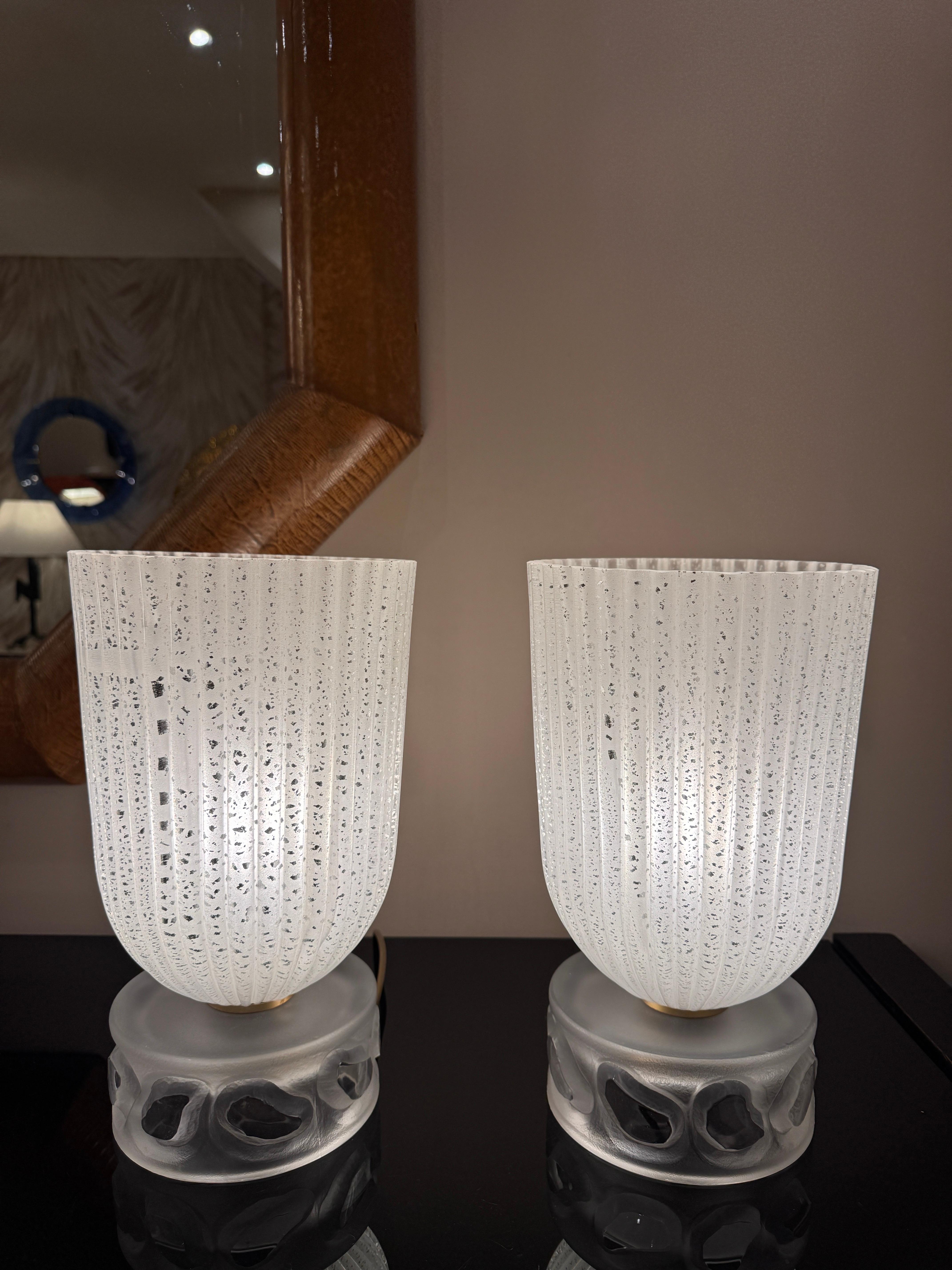Preciosa pareja de lámparas de sobremesa tipo antorcha/iluminador de diseño Art Déco francés . Tulipas totalmente de cristal estriado grabado al ácido con motas plateadas sobre una base decorativa de cristal esmerilado. 
2 conjuntos disponibles. 

