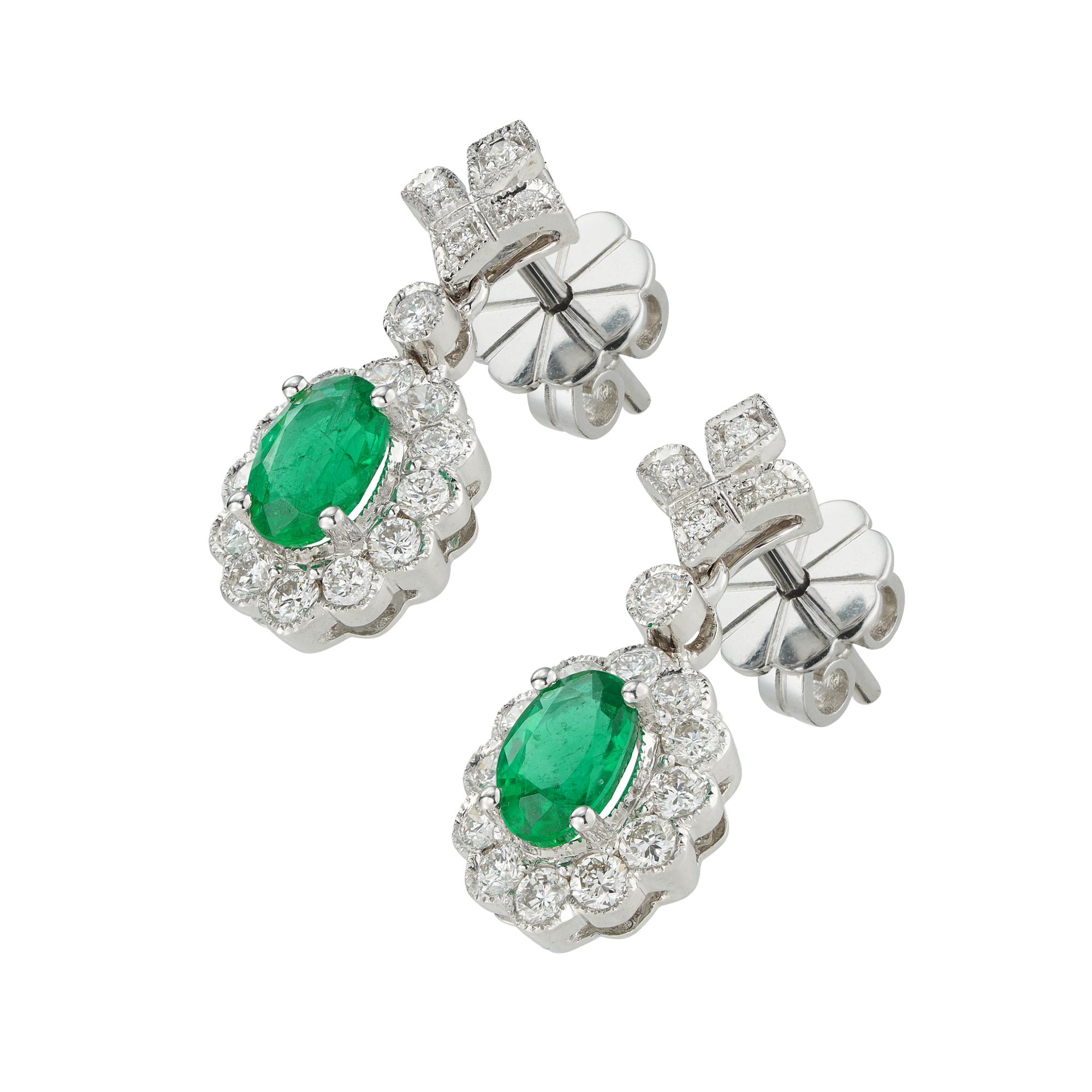A pair of emerald and diamond drop cluster earrings, the two oval faceted emeralds weighing 0.87 carats in total, each surrounded by twelve small round brilliant-cut diamonds and suspended by a fleur-de-lys diamond-set top, the diamonds weighing