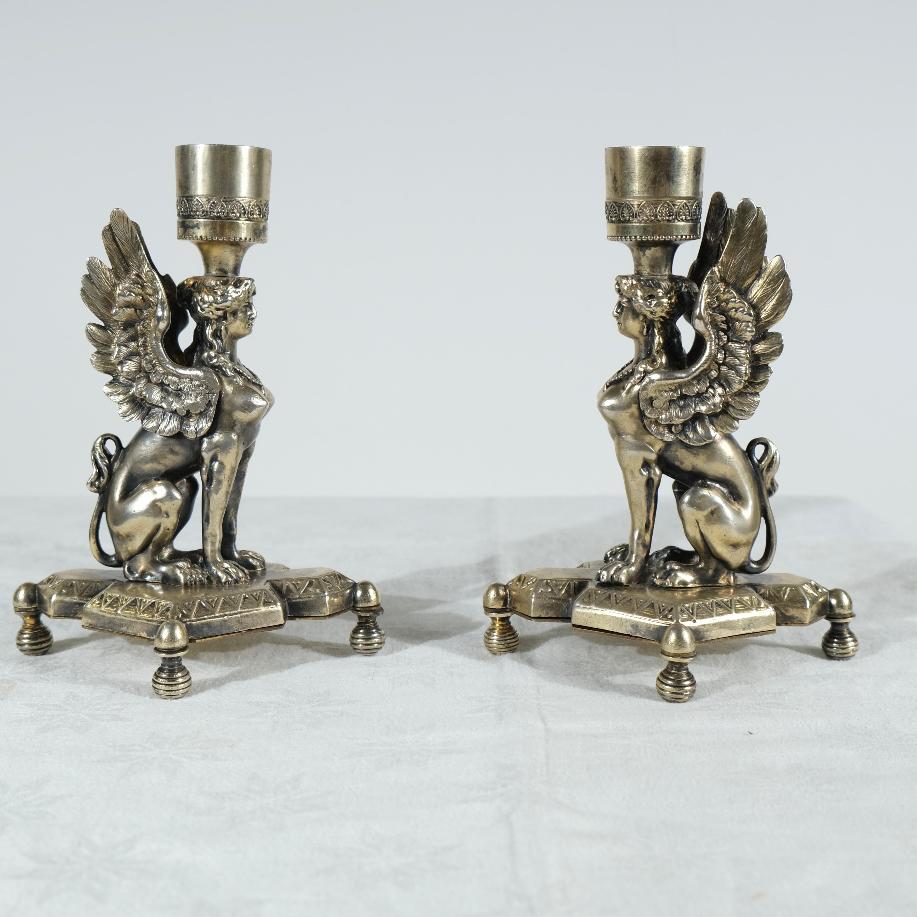 Questa splendida coppia di candelieri del periodo Impero, probabilmente di origine inglese, presenta un sorprendente design neoclassico. Realizzato con un'intricata attenzione ai dettagli, ogni candeliere è ornato da un motivo a sfinge alata