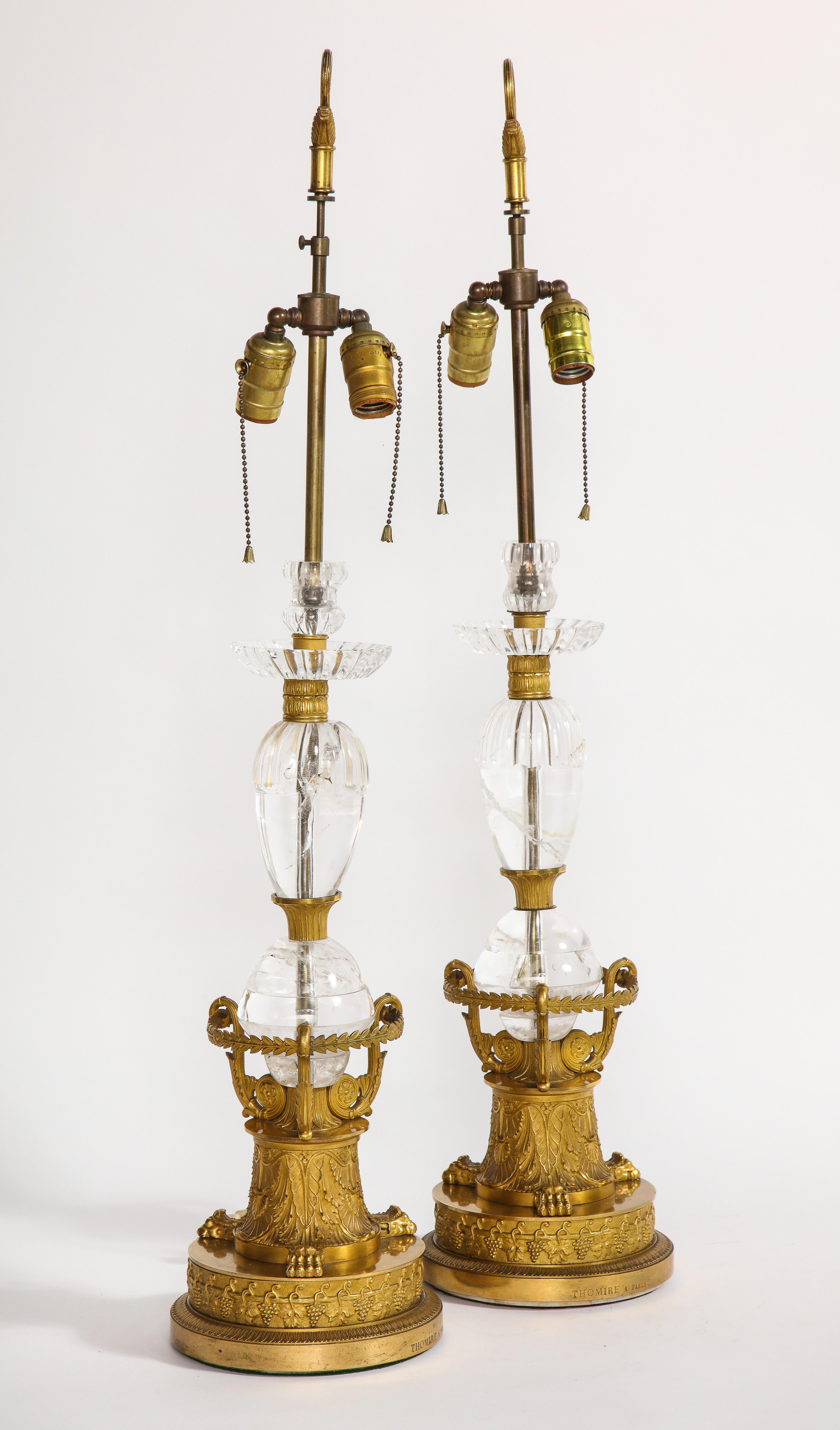 Une magnifique et très importante paire de lampes de table Empire en bronze doré et cristal de roche. Les deux sont signés sur la base Thomire à Paris. Chacune est minutieusement ciselée à la main et brunie avec de l'or bicolore. La base arrondie