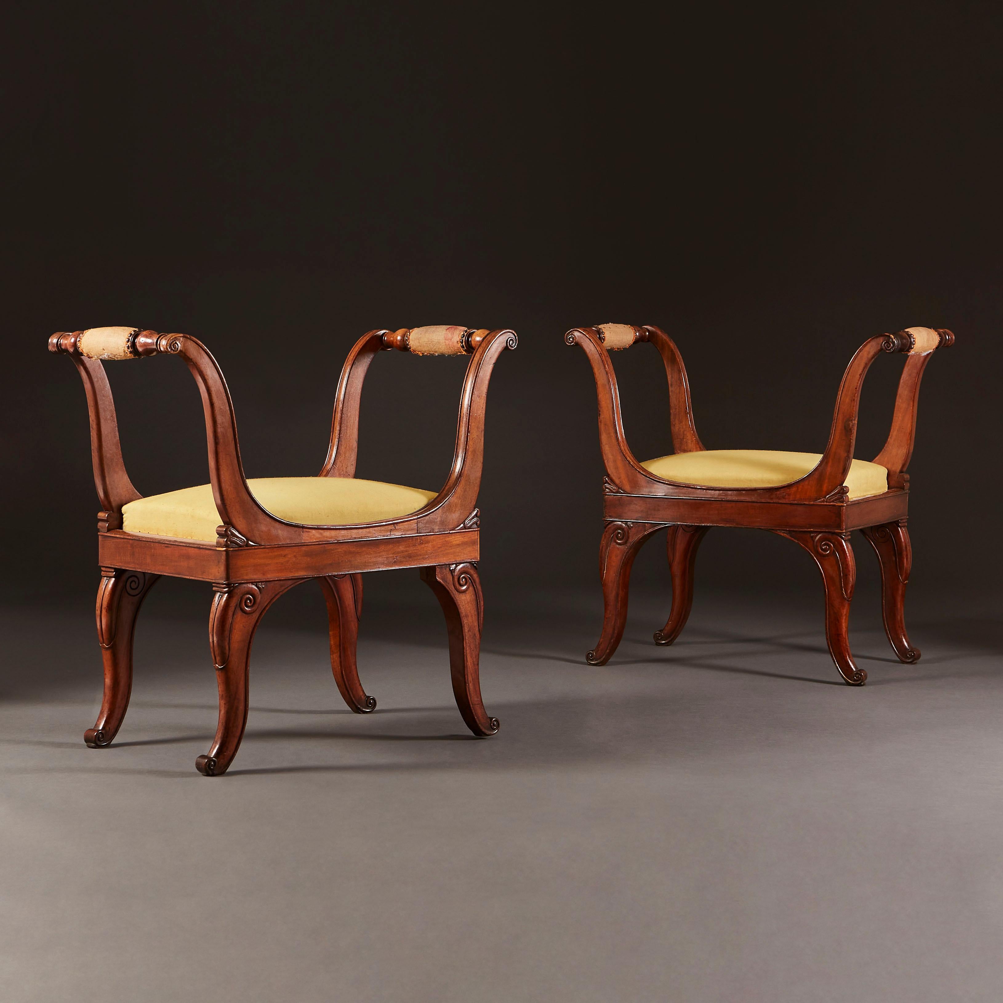 A fine pair of early nineteenth century mahogany stools with out swept arms, drop in seats, all supported on splayed legs.
    
