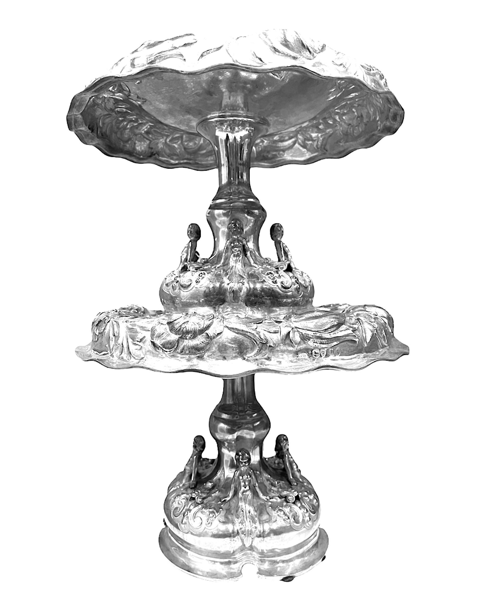 A pair of English 19th century (1875) Victorian silver tazze by Alexander MacRae. These are boldly chased with flowers and foliage, the bases applied with demi-figures and a shield engraved with arms. Both pieces are marked by the artist including