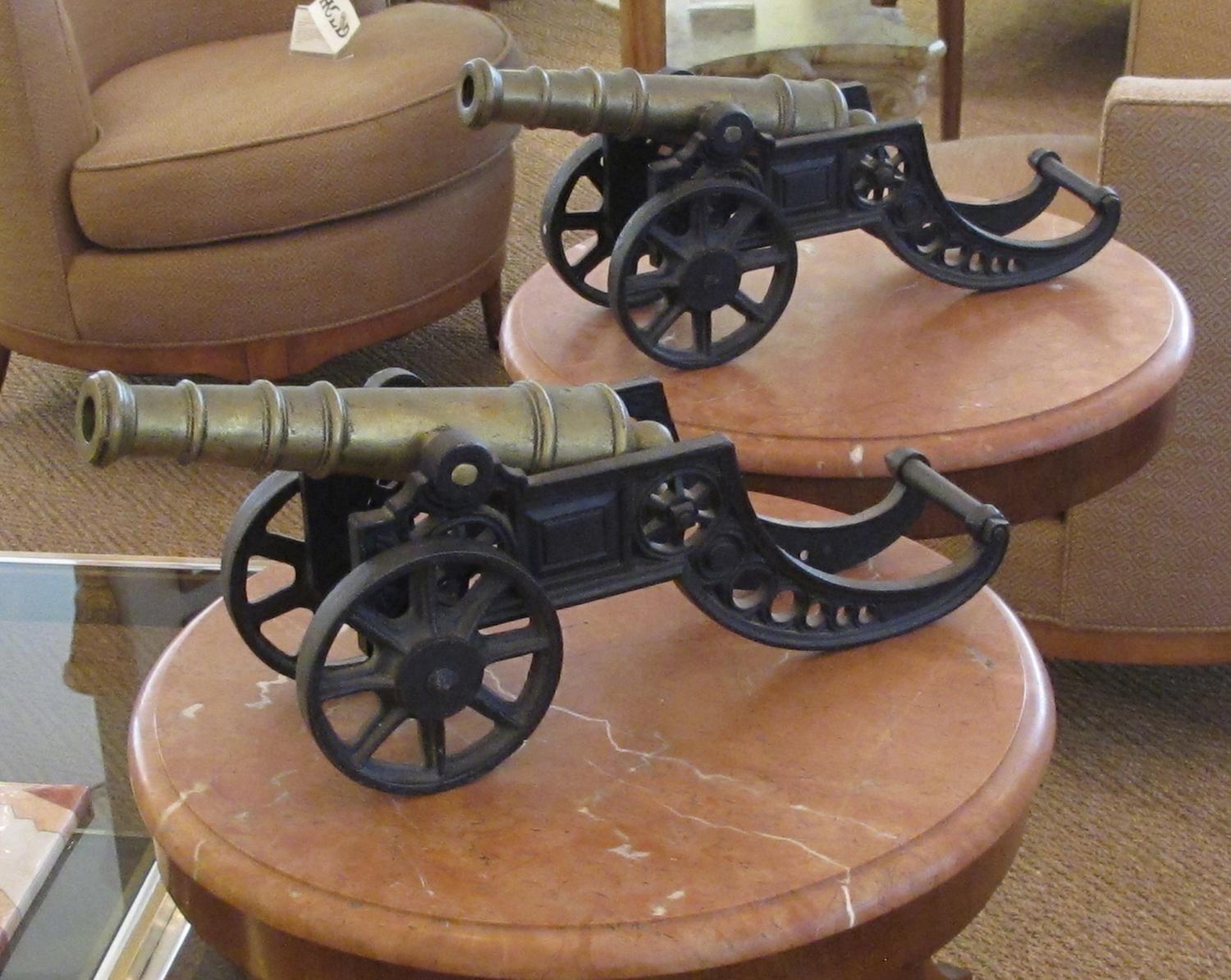 Each with solid brass tilting barrel resting on a heavy iron carriage with working wheels; finely and realistically decorated.