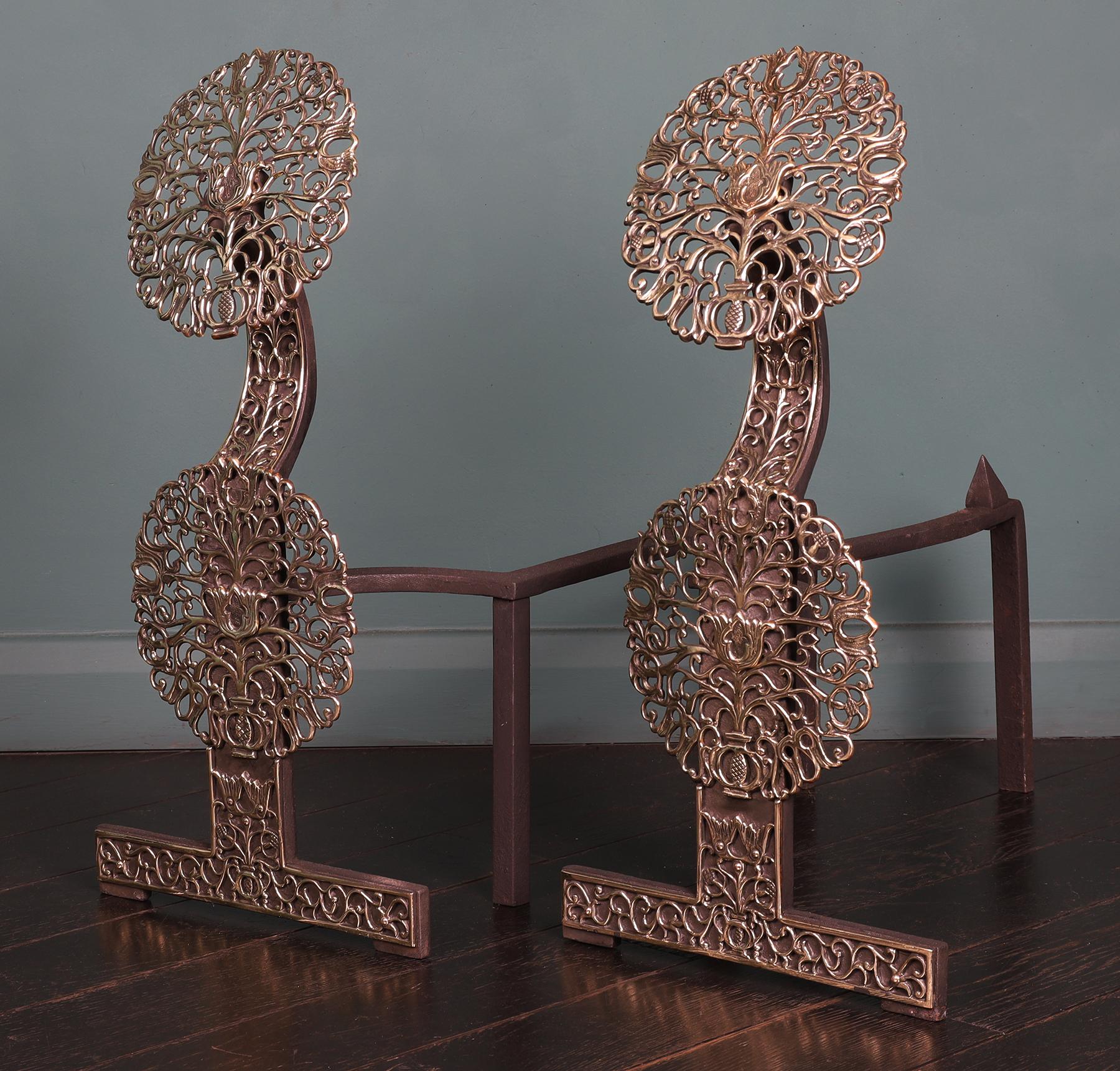 The design for this pair of English andirons first originated in the late 17th century. The pierced ornamental brass discs are set one above the other and in contrast to the wrought iron standards. The rear log supports can be adjusted to fit the