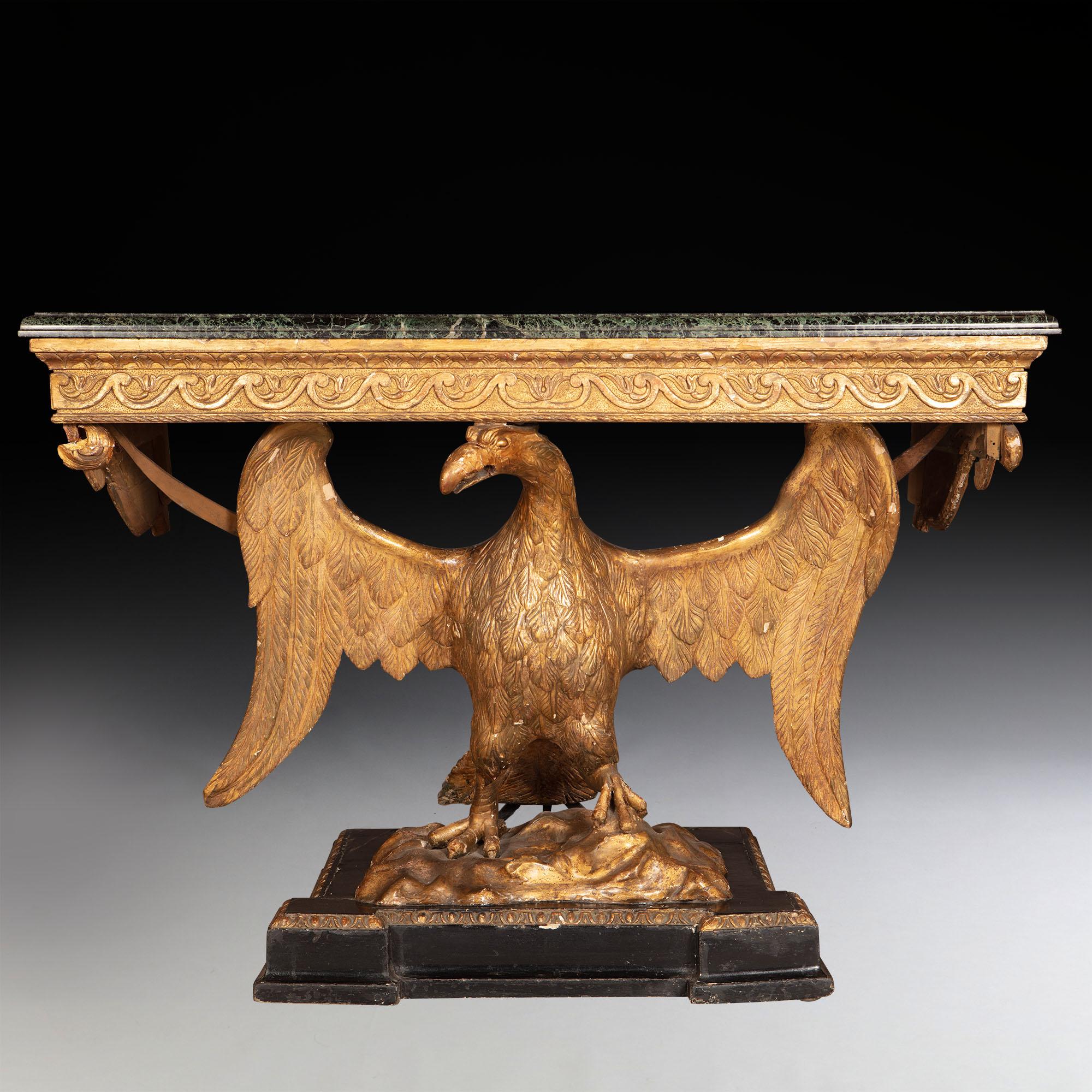 A fine pair of George II style giltwood eagle consoles
The original verde antico rectangular marble tops with a moulded edge, above a vitruvian scroll giltwood frieze supported by carved giltwood winged eagles, standing on rock work ground, above
