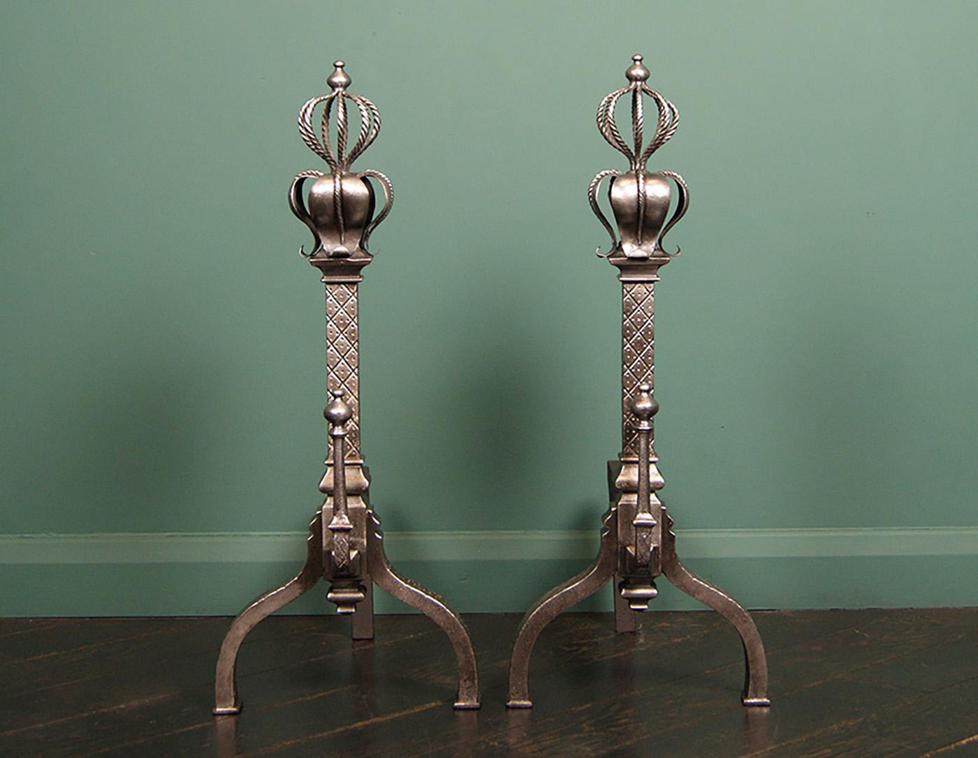 A finely crafted pair of English Gothic-revival andirons in iron with wrought crown and leaf repousse-work over engraved shafts on arched supports.
Restored.
Circa 1860