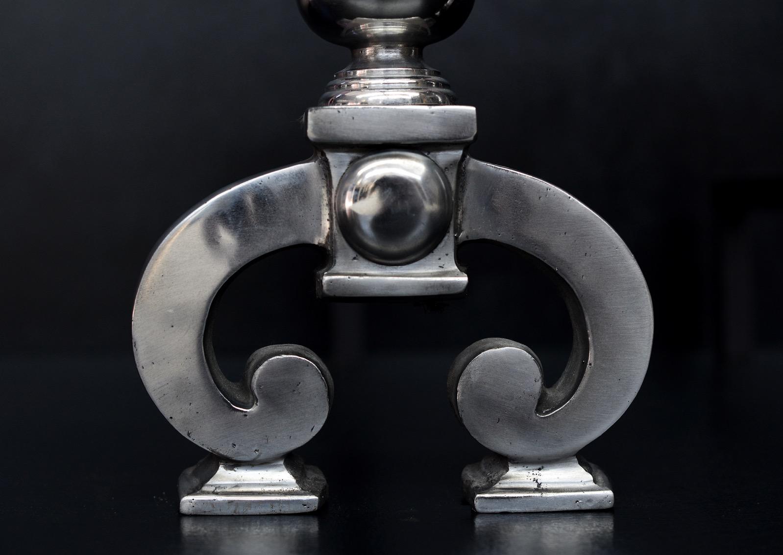 Paire de chenets anglais en acier poli, avec des pieds en forme de fer à cheval, un fleuron en forme de balustre, surmonté d'un sommet bombé et perlé. Moderne. N.B. Peut être soumis à un délai de livraison prolongé.

Mesures : Hauteur : 545 mm 21