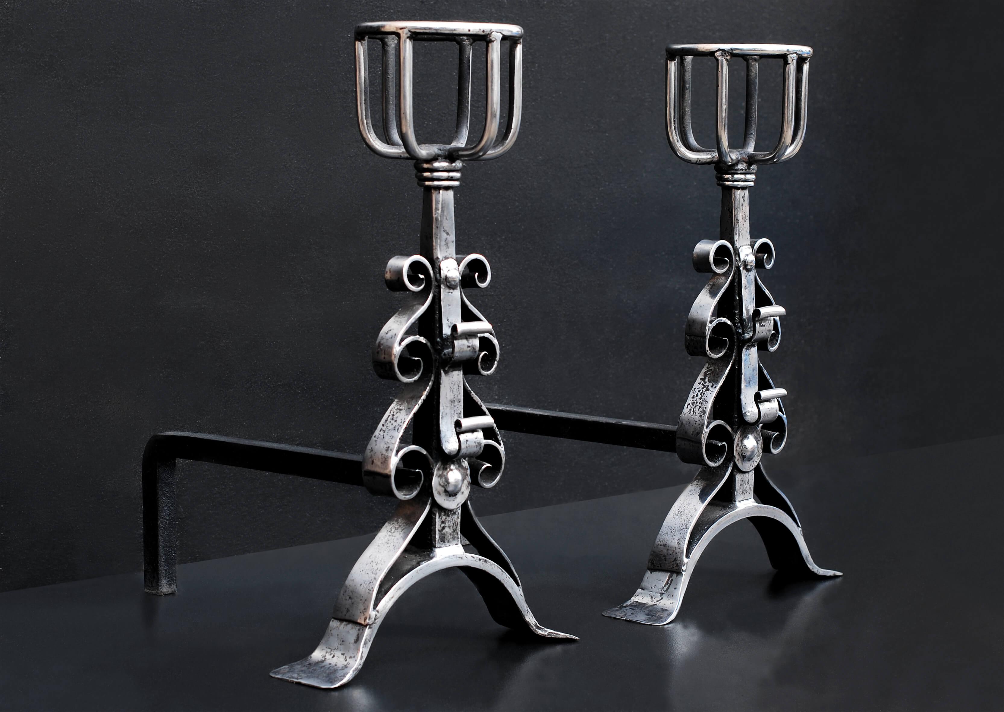 A heavy pair of polished wrought iron firedogs. The arched feet surmounted by scrolled motif to shafts and mulling tops. English, 19th century.

Height:	610 mm      	24