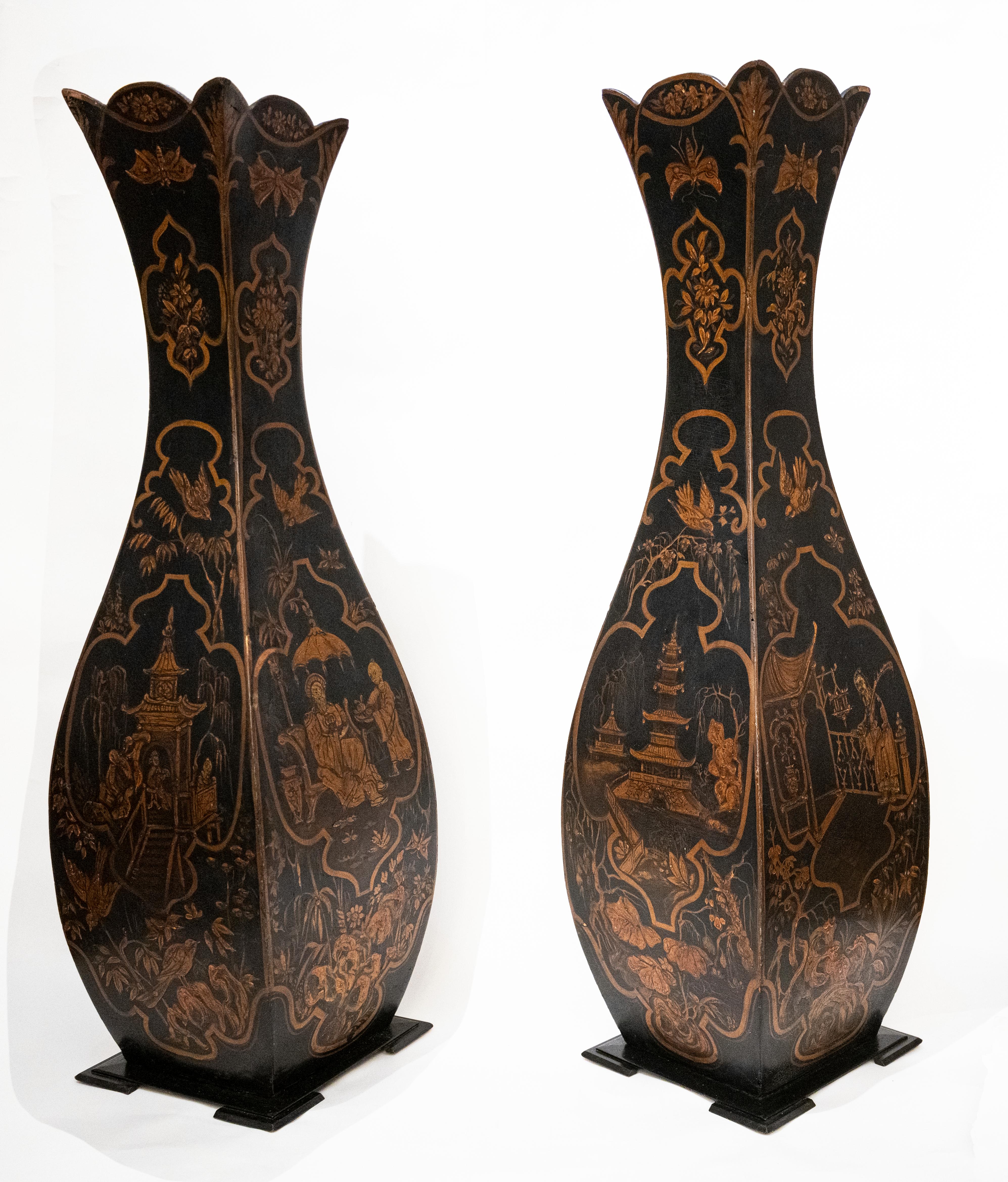 A pair of English wood and paper mache oversized vases. The overscaled form with cartouches having hand painted chinoiserie decorations in gold with a black ground, with individual craquelure? Has square footed bases and scalloped tops. Provenance: