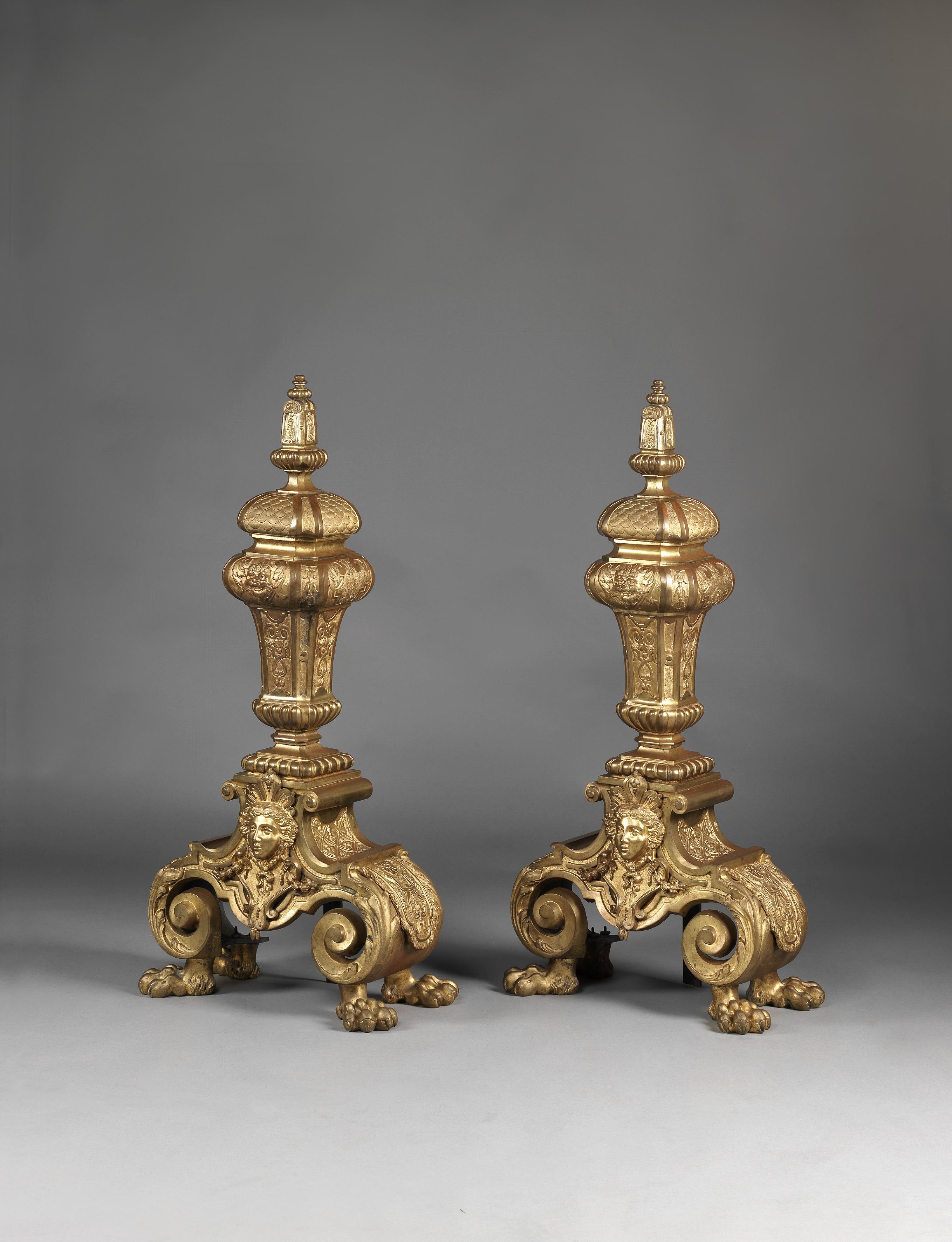A pair of exceptionally large Regence style gilt-bronze chenets.

French, circa 1860.

Each of tapering baluster form, centred with a mask, on a scrolled base with paw feet.