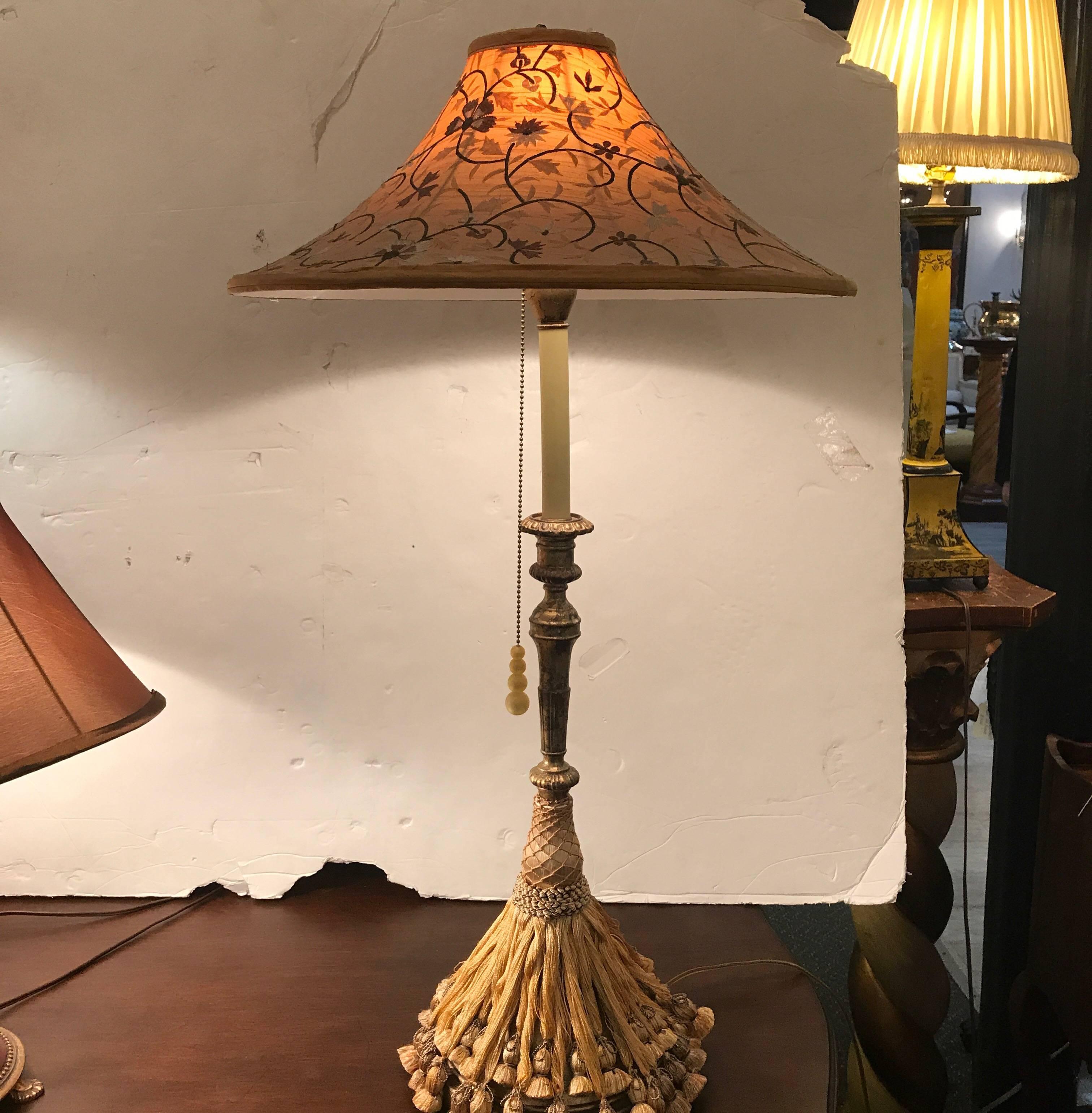 A pair of extravagant lamps with embroidered coolie shades designed by Traynor for Frederick Cooper. The tall lamps in a gilt metal candlestick form. The bases are draped with layers of tassels for a very unique look. The dramatic shades with all