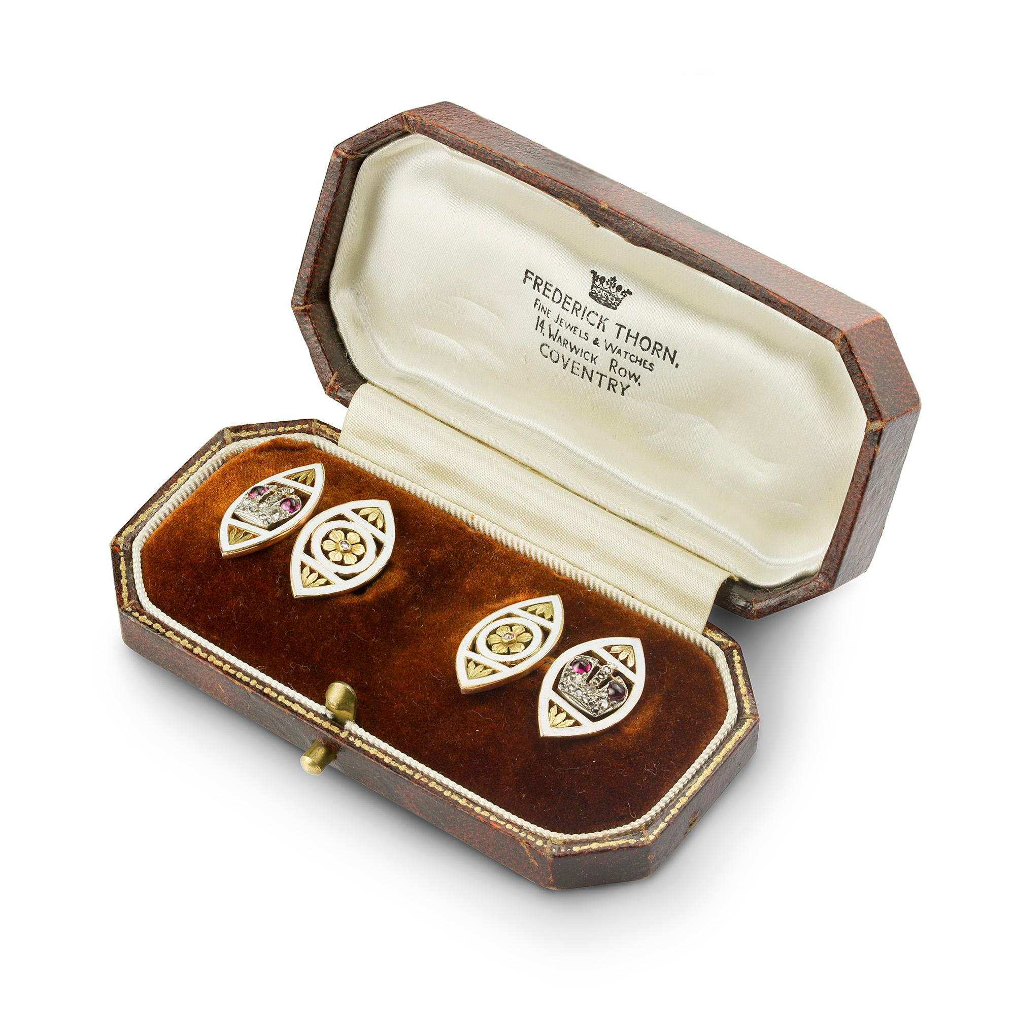 A pair of Faberge ruby and enamel cufflinks, each cufflink comprising two marquise-shaped plaques, one with the Russian Imperial crown set with cabochon rubies and rose-cut diamonds surrounded by white enamel linked by a gold chain to the other