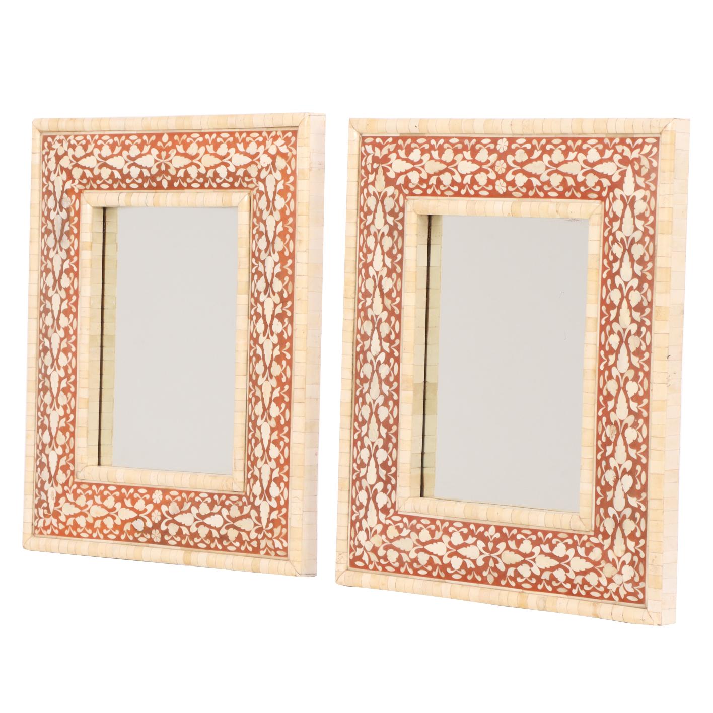 A decorative pair of contemporary mirrors from India, each featuring a floral motif in faux bone inlay. The light, intricate patterning adds texture and elegance, making them ideal for brightening an entryway, bedroom, or living space. Their