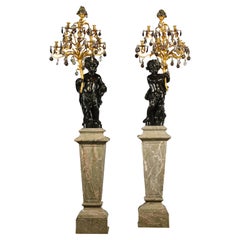 Pareja de candelabros figurados Putto de siete luces, sobre pedestales de mármol verde