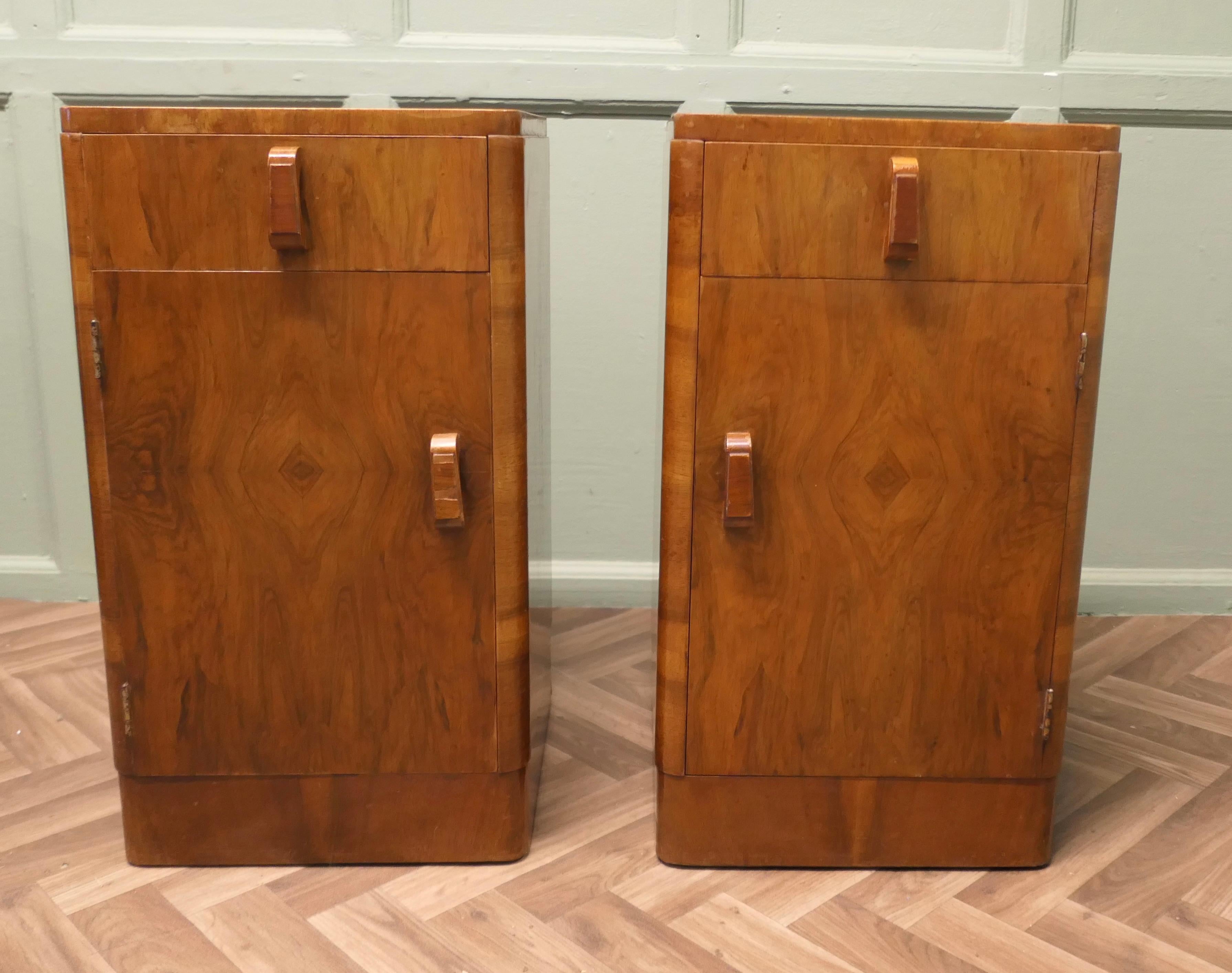 Paire de tables de chevet Art Déco en noyer sculpté
  
 Il s'agit d'une paire très élégante, chacune ayant un tiroir au-dessus d'une armoire à étagères, les armoires ont des poignées en bois sculpté faites à la main.

Les armoires sont en bon état,