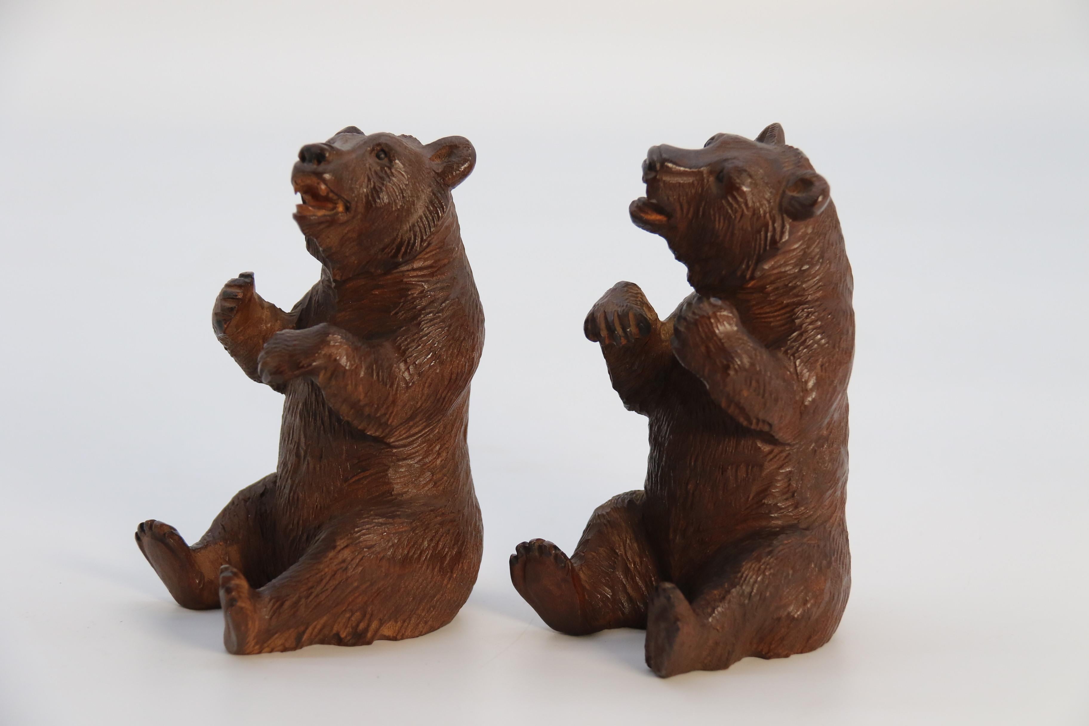 Dieses bezaubernde Paar sitzender Schweizer/Deutscher Schwarzwaldbären aus Lindenholz ist selten als Originalpaar erhältlich. Sie sind wunderschön handgeschnitzt und es gibt sie für Links- und Rechtshänder. Der Künstler hat sein Motiv mit viel Liebe