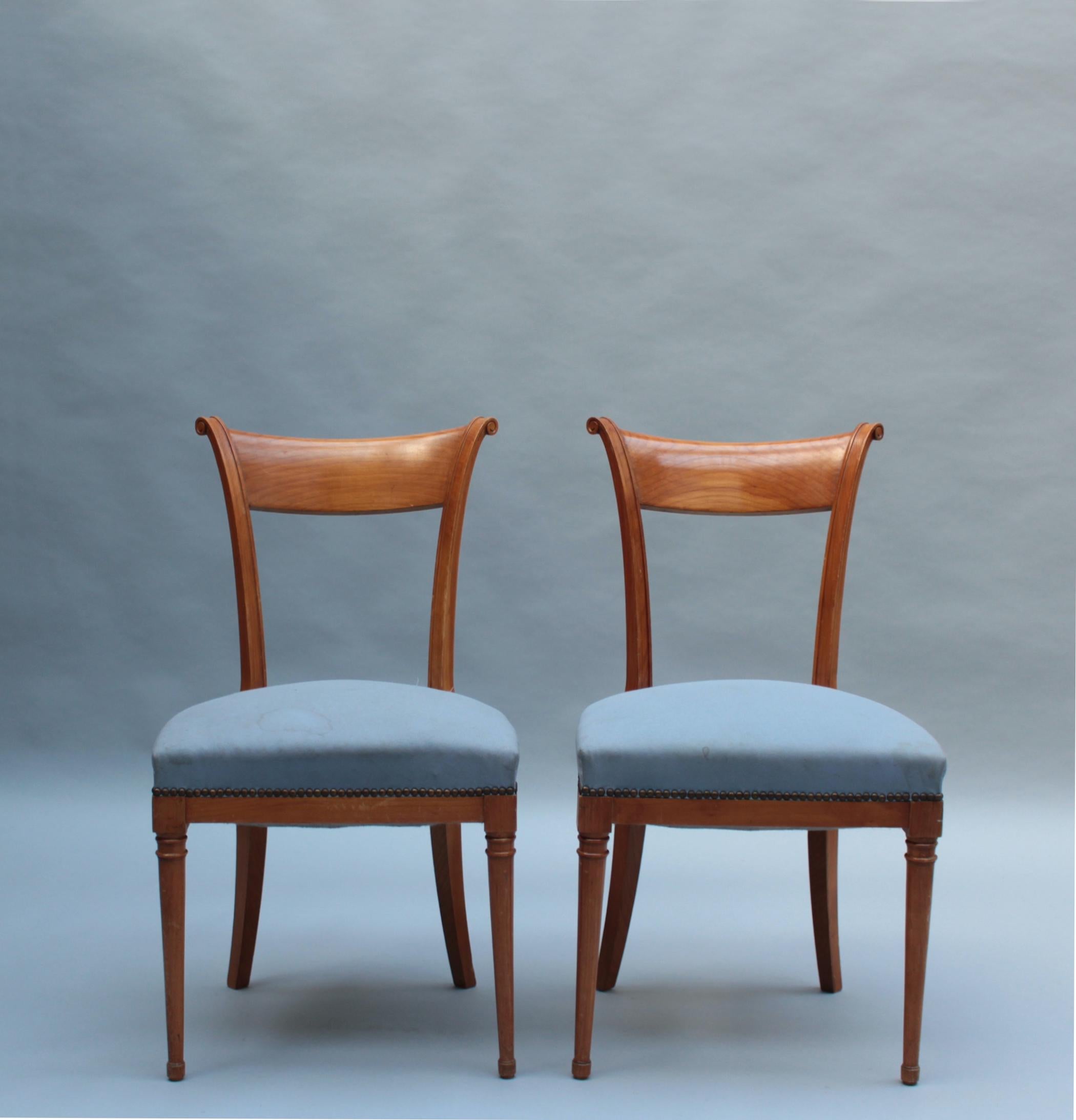 A pair of fine French Art Deco cherrywood side chairs with a curved back, fluted back post, and turned wood details on front legs.

