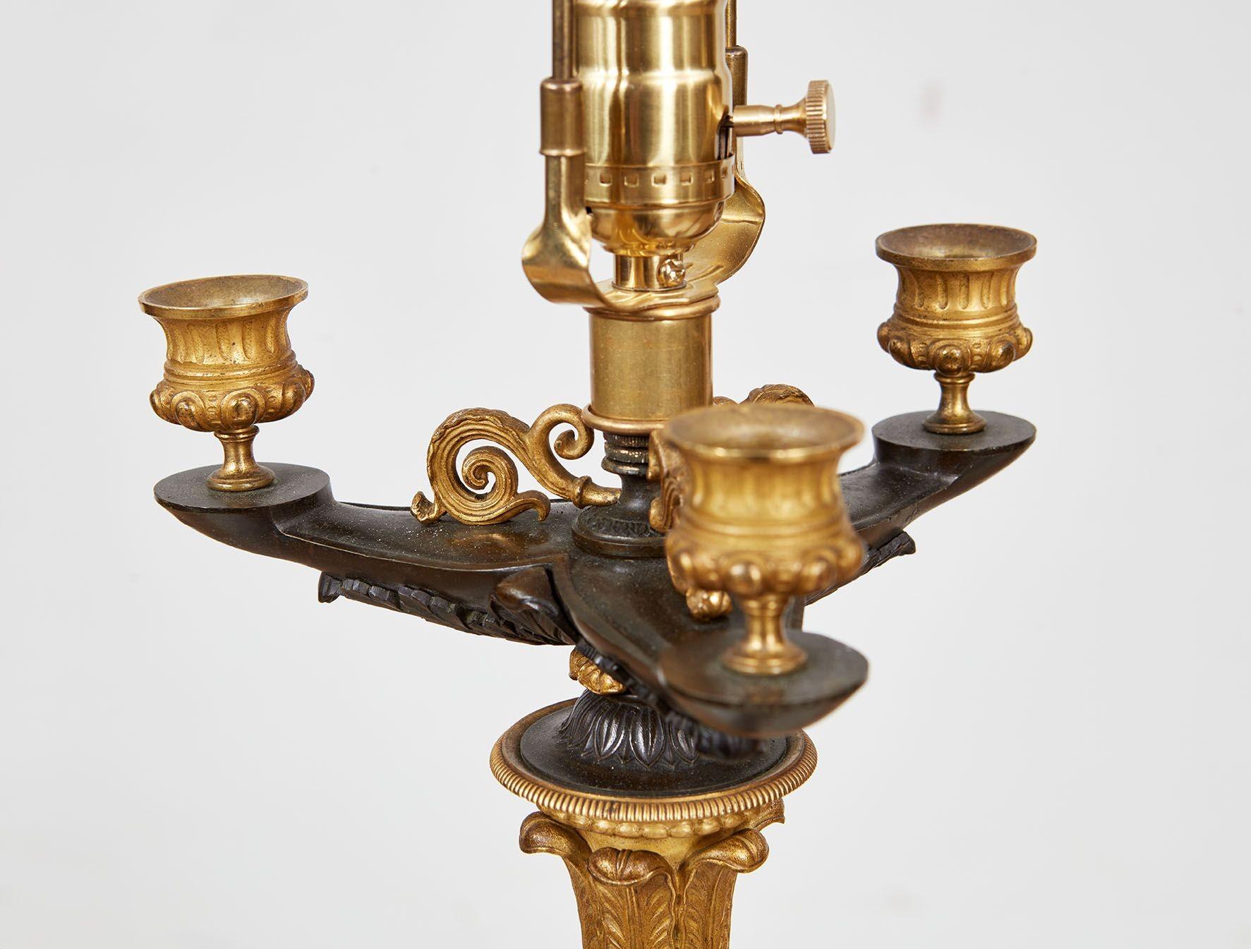 A pair of Charles X candelabra in patinated dark bronze with gilt bronze highlights having fine detailing throughout, now as table lamps.  Very elaborate neoclassical detailing, including bobeches over ribbed column with acanthus collar and stem on