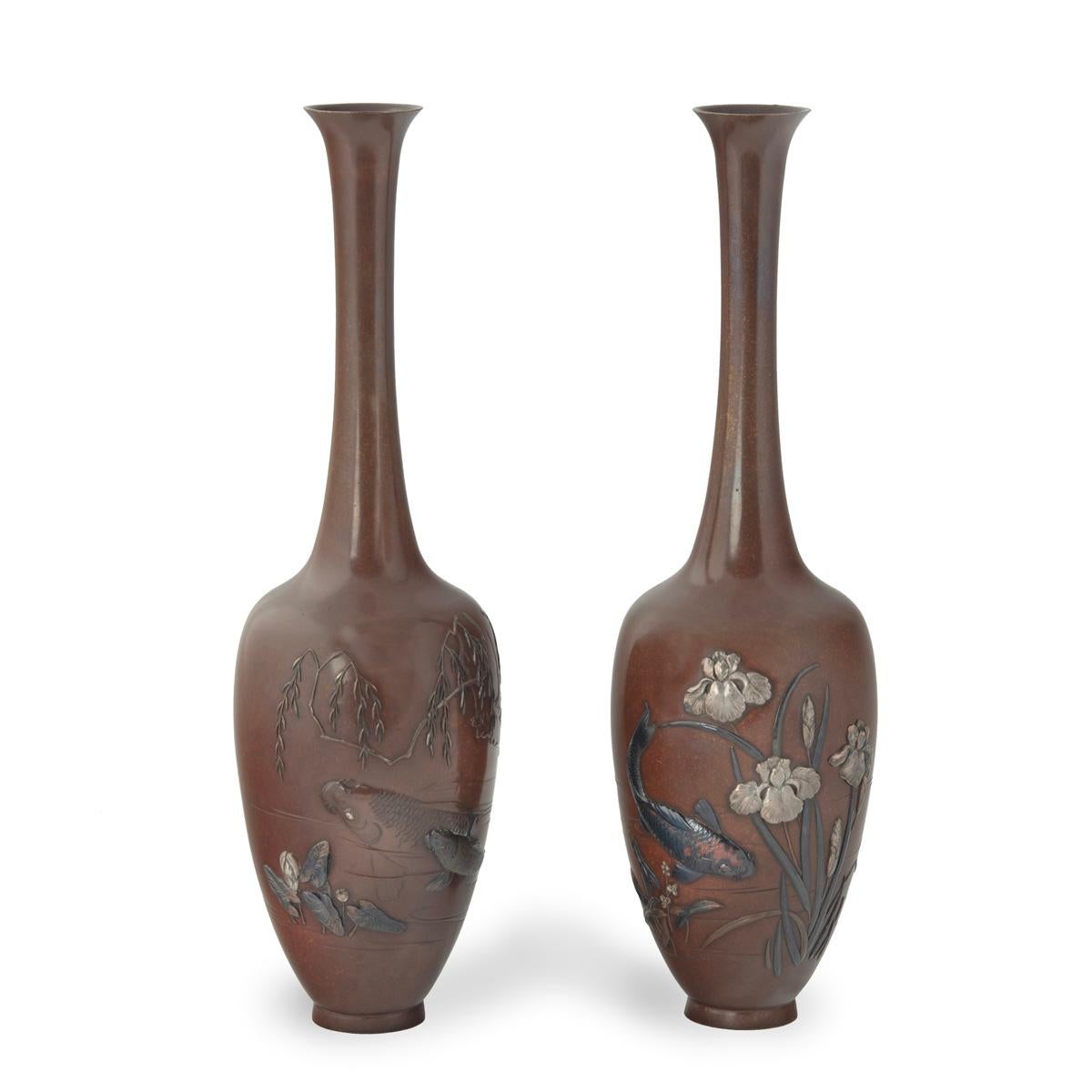 A pair of fine Meiji period bronze vases by Hidenobu, each of slender baluster form with and elongated neck, worked in silver, shakudo and patinated bronze with carp swimming amongst iris plants and trailing willow branches, signed Hidenobu-koku秀延刻.
