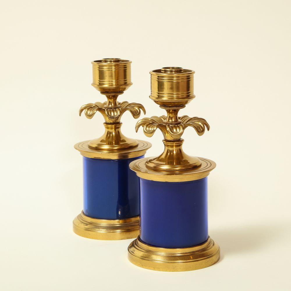 Each with nozzle set within a round collar set above a turned stem with a ring od furling foliage; supported on a blue-enameled cylindrical pedestal with gilt bronze capital and base.