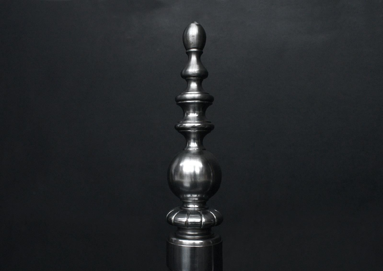 Une paire de chiens de garde en acier poli. Les pieds arqués, avec un fleuron godronné au centre, sont surmontés de tiges tournées. Anglais, moderne. 

Hauteur :	475 mm      	18 ¾
