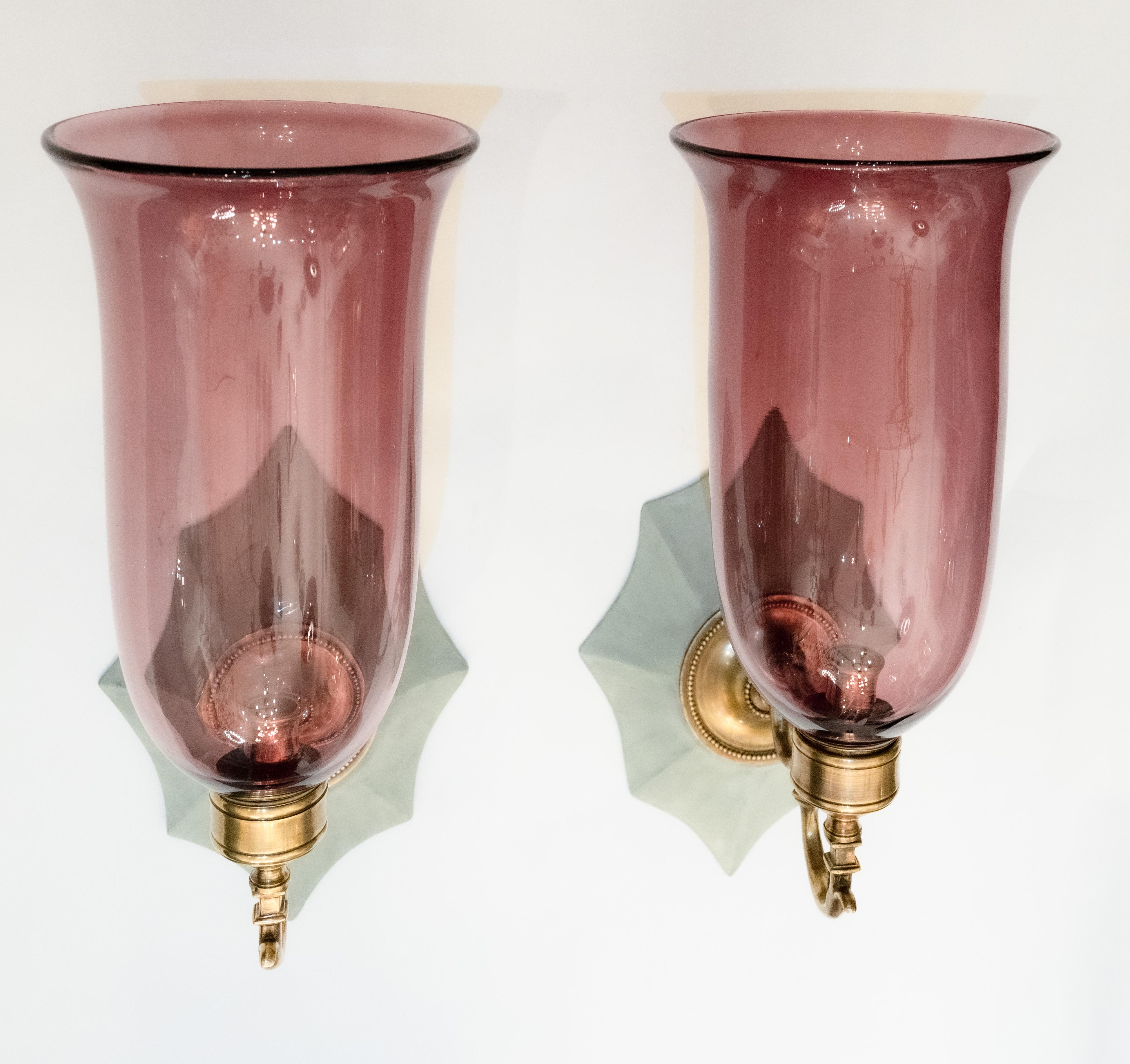 A pair of hand-carved Boissy sconces from mahogany Georgian-style backplates with a painted finish, patinated brass sconce fittings, and hand-blown flared shades. Electrified with one candelabra-based socket per sconce. Our custom hurricane sconces
