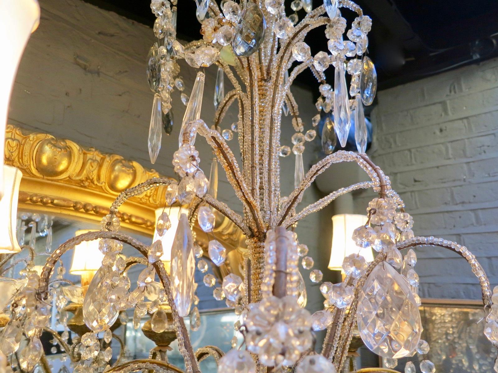 A 20th century pair of Florentine style Italian chandeliers, with six arms, gold gilt and multi coloured cut glass on beaded iron frames.