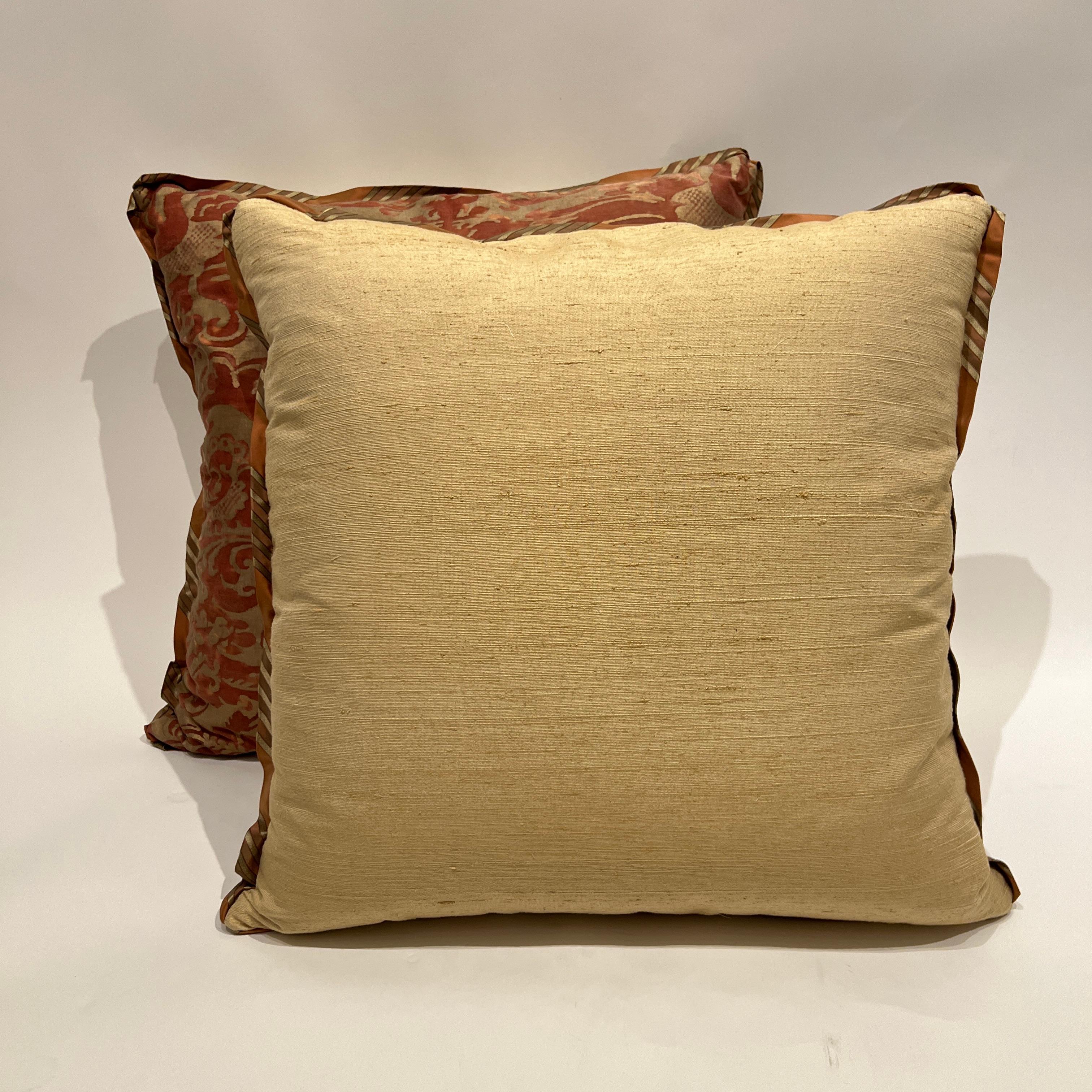Une paire de coussins Fortuny dans le motif Sévigné dans un coloris rouille et or. Avec une bordure de soie rayée en biais et un support en soie thaïlandaise.