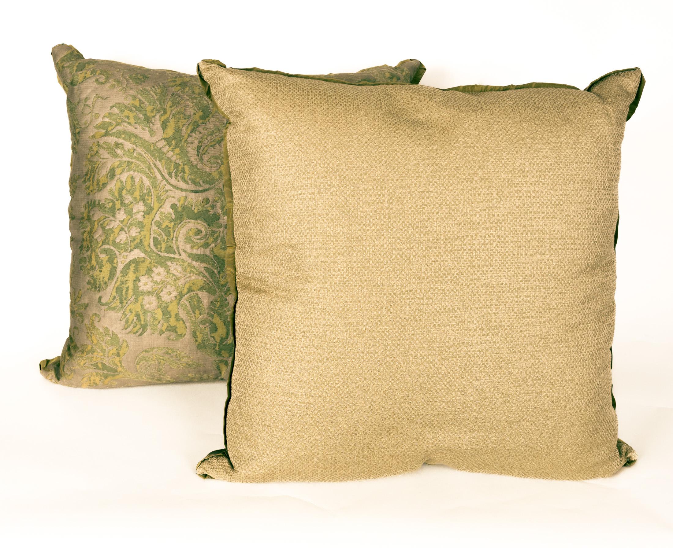 A pair of Fortuny fabric cushions in the DeMedici pattern, green and silvery gold color way with silk bias edging and silk blend backing material, the pattern, a 17th century Italian design named for the famous Florentine family, the Medici. Newly