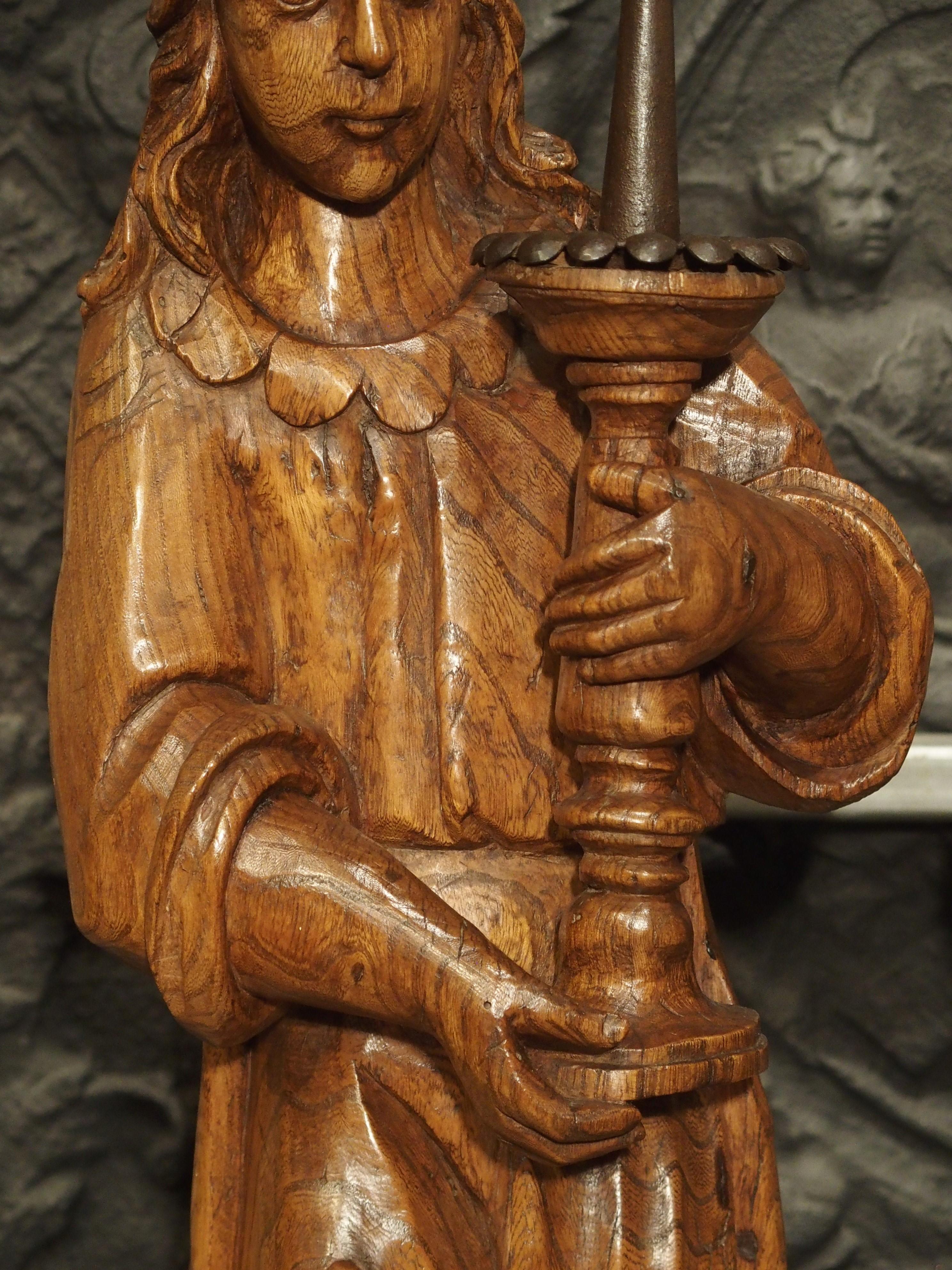 Standing at over two feet tall, this 17th century pair of angel candlesticks has been carved out of a beautiful French elm wood. Because elm wood typically has an interlocked grain, it can be quite difficult to carve or split. These candlesticks