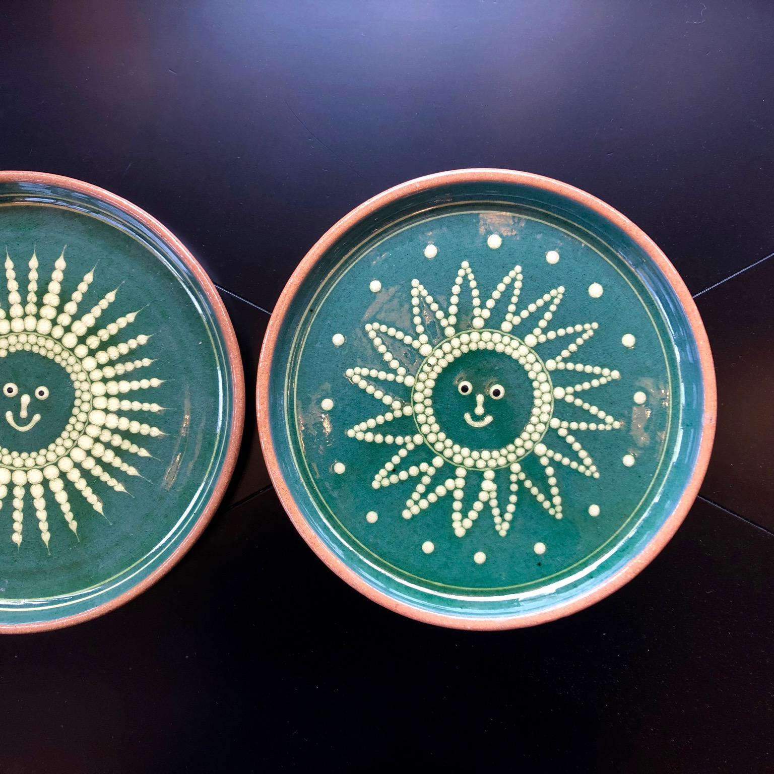 2 x French 1950s green glaze and terracotta plates depicting sun and moon. Initials impressed underneath.