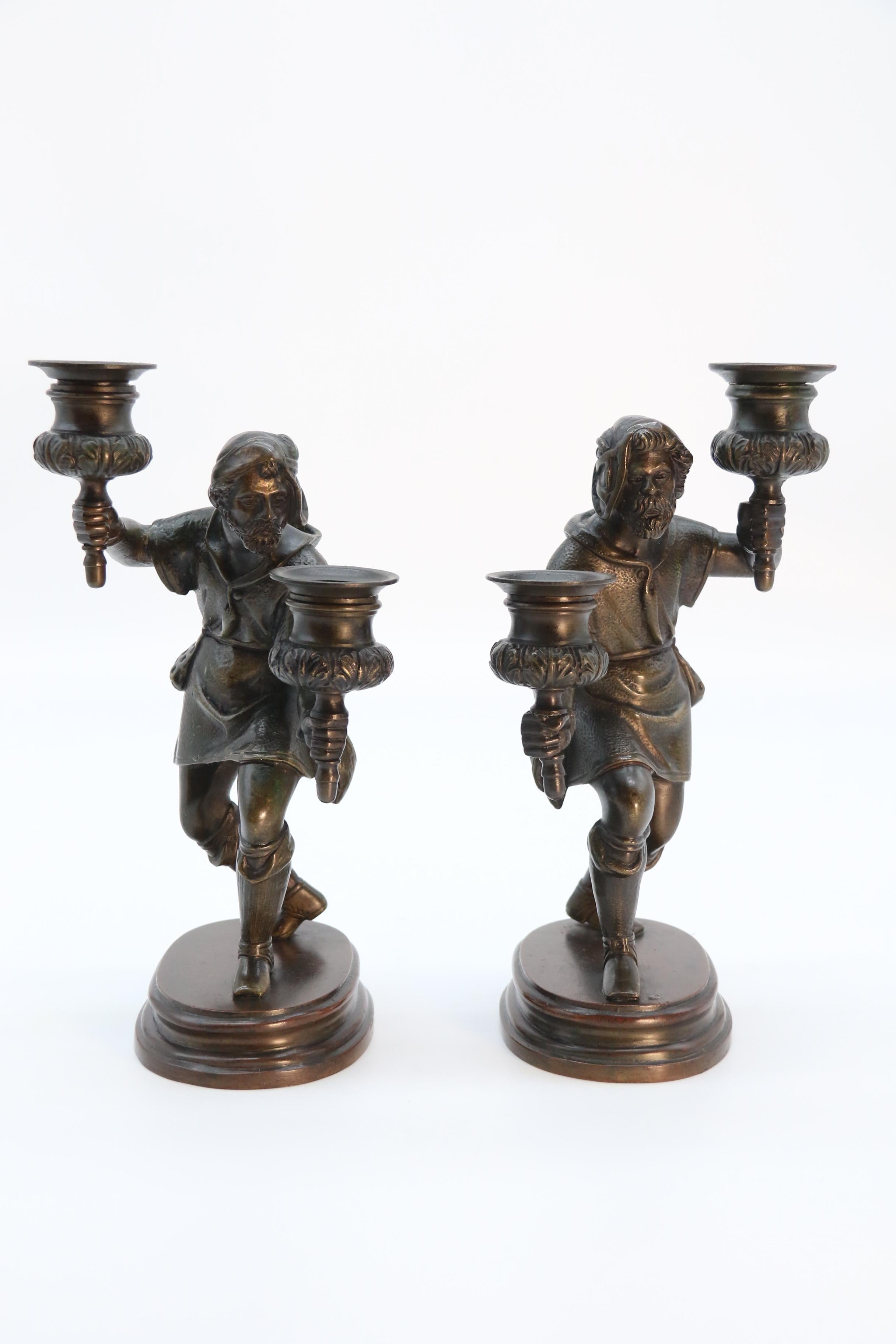 
This highly decorative pair of mid 19th century bronze double candlesticks are beautifully cast in solid bronze. They have very good detail and are each in the form of a medieval watchman who is modelled wearing a simple hat, robe and leggings with