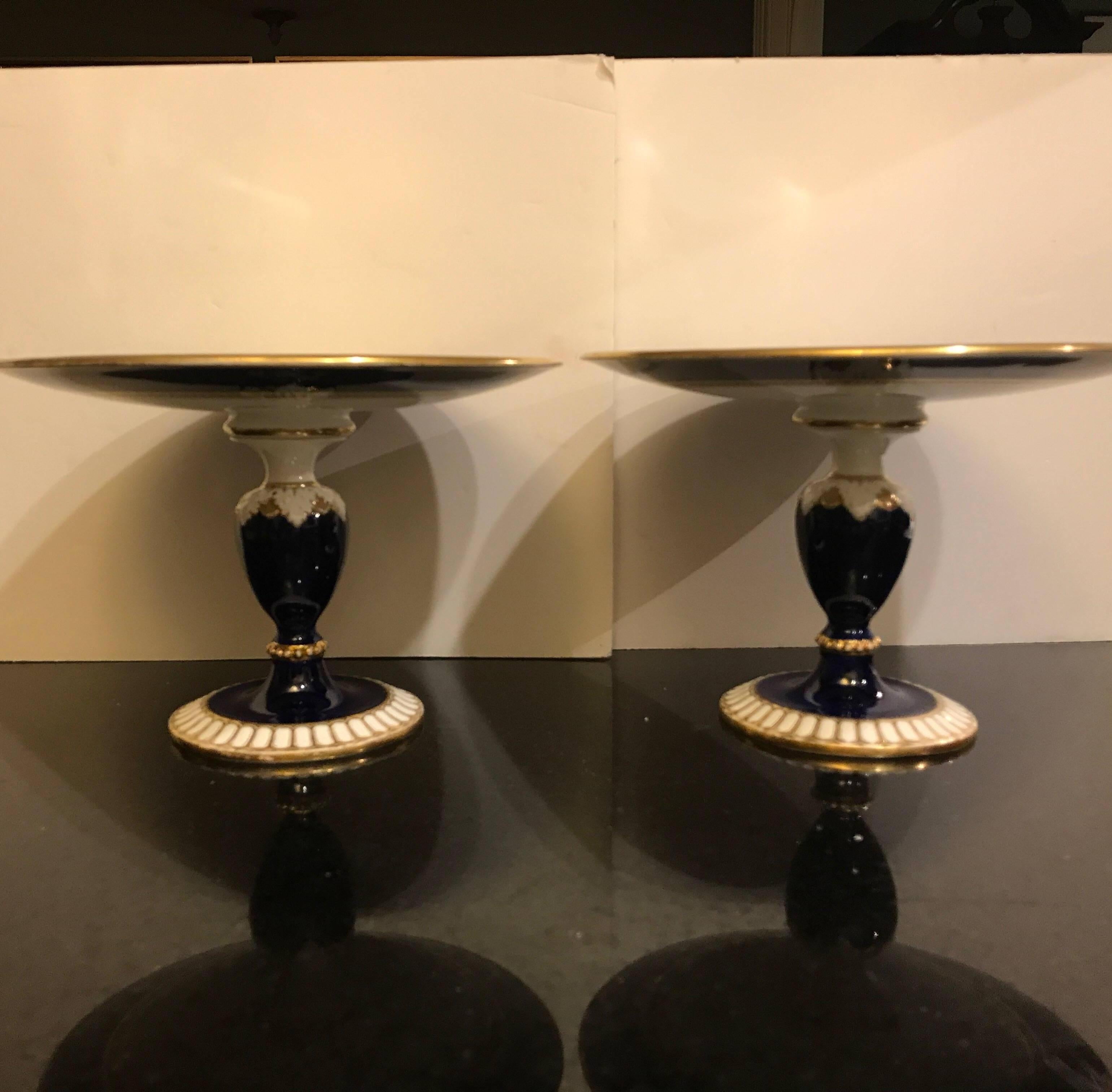 Elegant pair of porcelain compotes with had painted gilt decoration, the cobalt bases with gilt trim with upper white and cobalt dish tops. The compotes are just under the size of a luncheon plate at 9.5 inches.