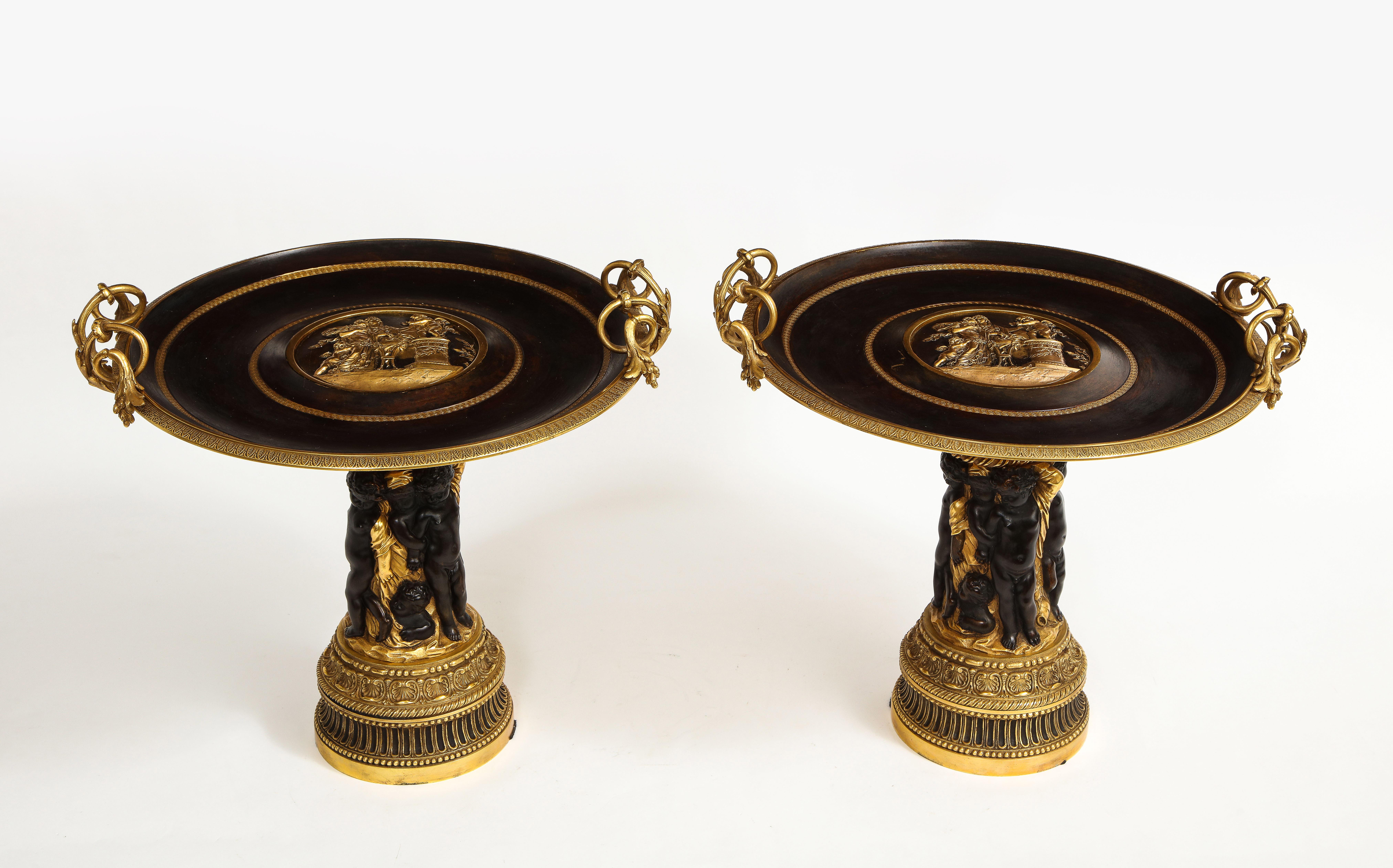 A fantastic pair of French 19th century Napoleon III period patinated and dore bronze tazzas/centerpieces. Each circular tazza top is beautifully patinated and further decorated with dore bronze rings. The center of each tazza top is complete with a