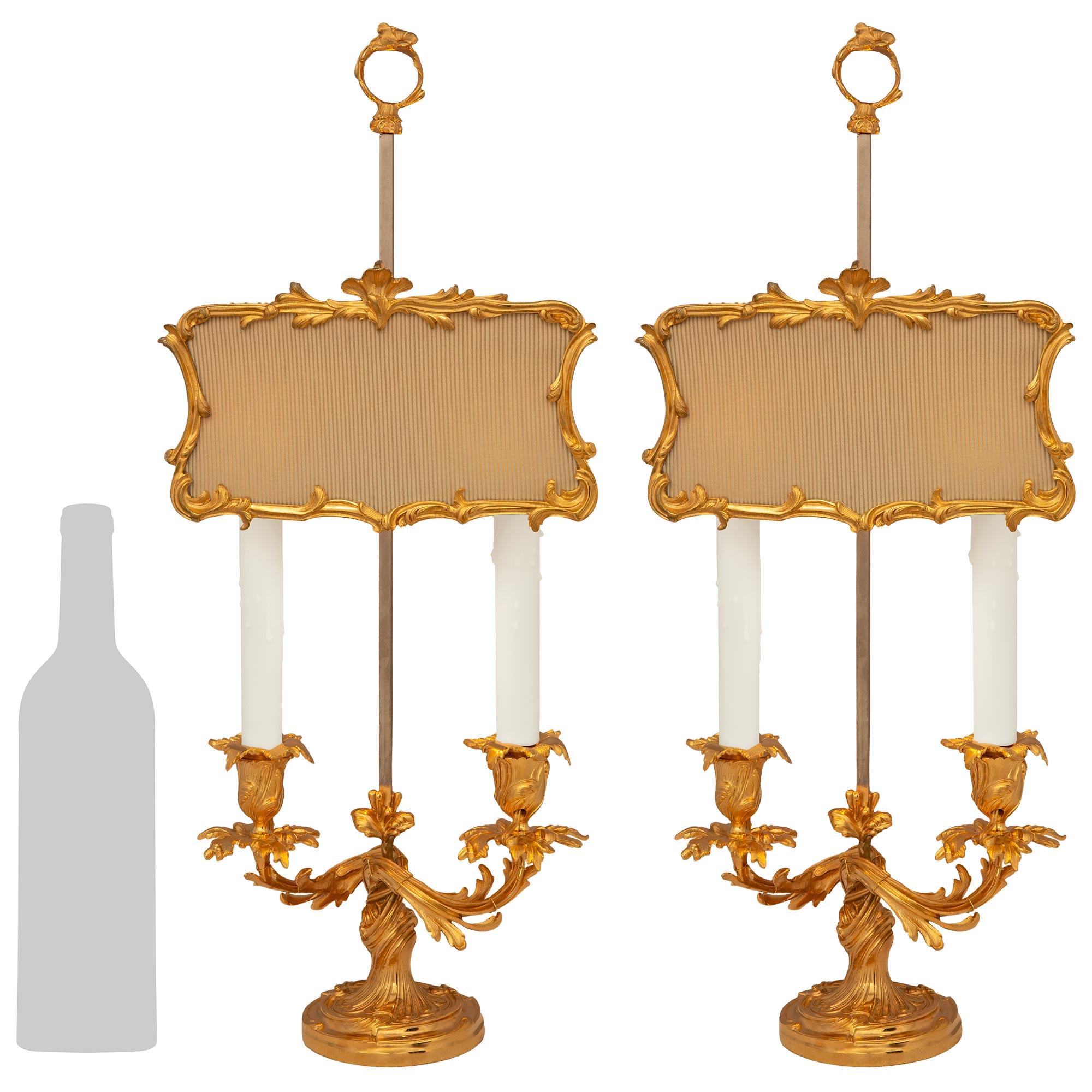Una splendida e decoratissima coppia di lampade a candelabro francesi del XIX secolo in stile Luigi XV. Ogni imponente candelabro a due bracci è sollevato da una base circolare a forma di socle con bordi screziati e movimenti a scorrimento. Sopra la