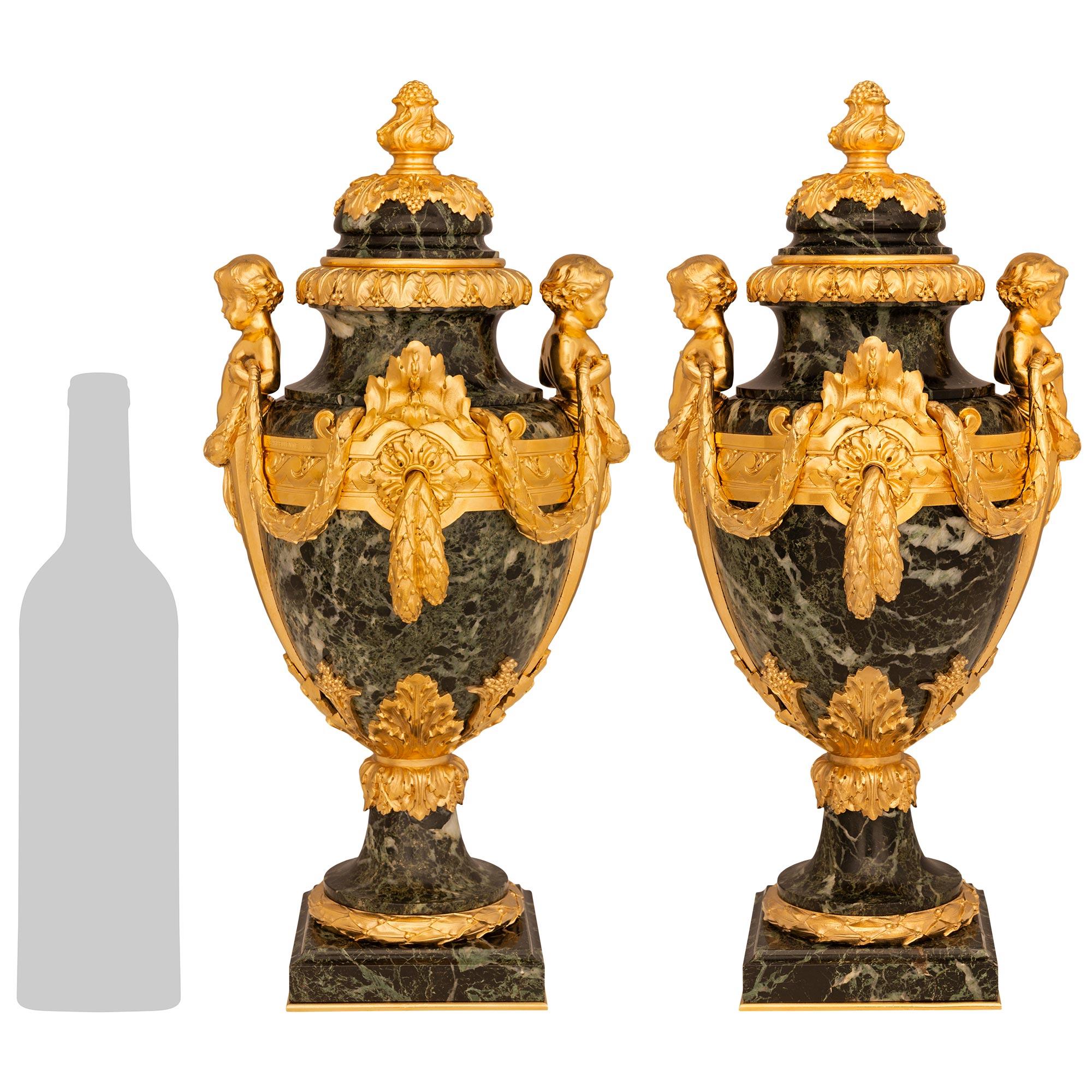 Una coppia elegante e di alta qualità di urne francesi del XIX secolo in stile Belle Époque in marmo Greene & Greene antico e Ormolu, firmate F. Barbedienne. Ogni squisita urna è sollevata da una base quadrata in marmo con una piastra inferiore in